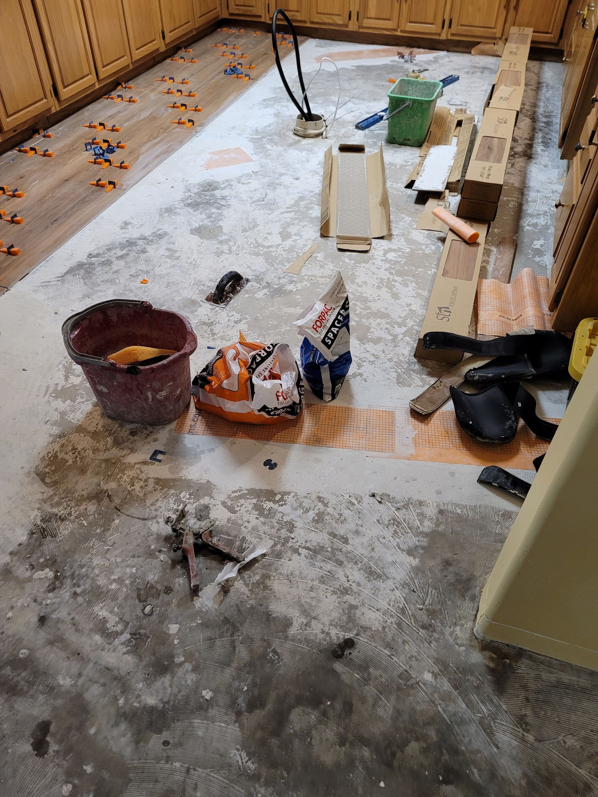 Partially renovated room with tools, lumber, buckets, and construction debris on the floor