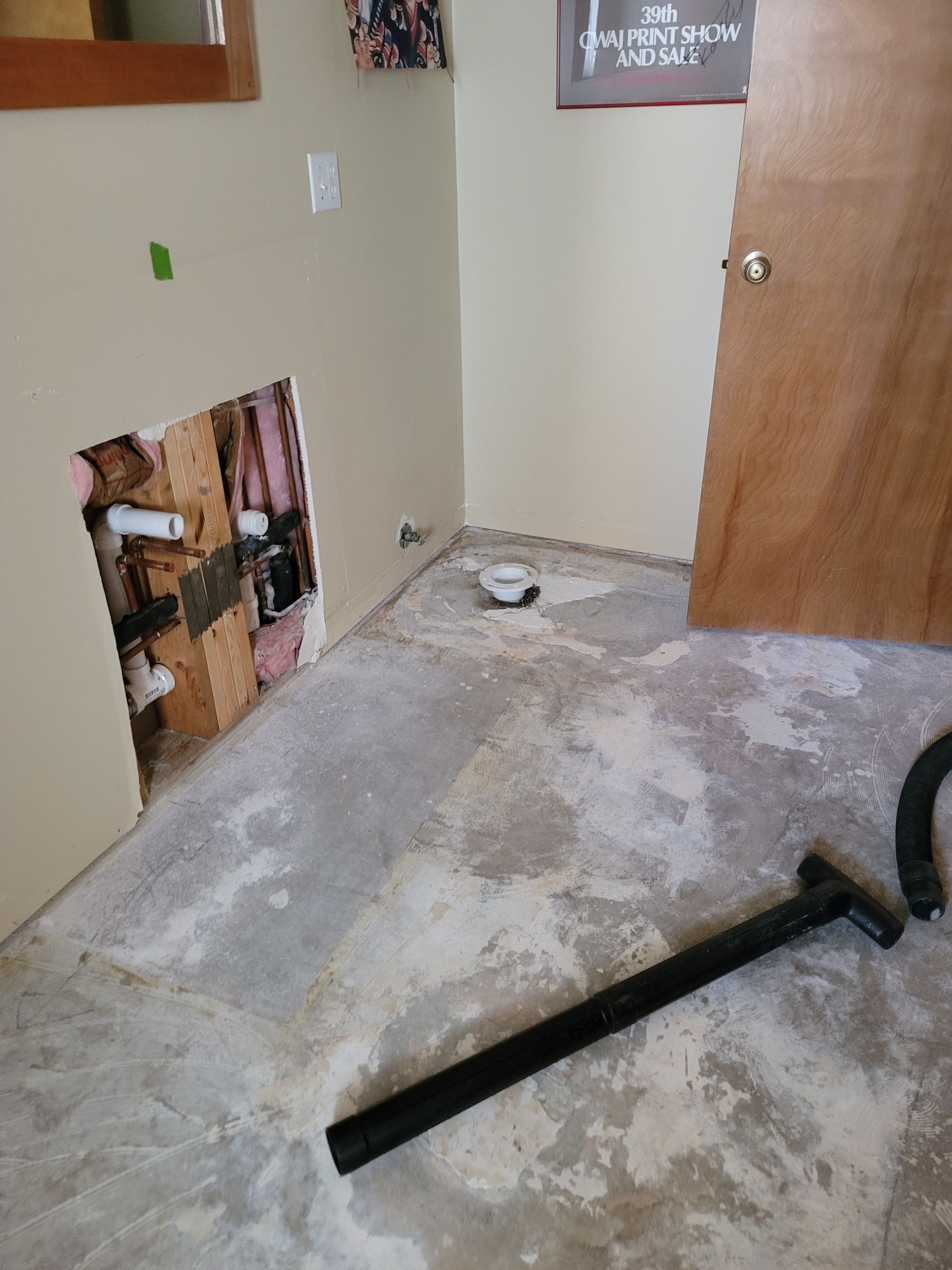 Damaged hallway floor with exposed area, scattered debris, and a black pipe across the carpet.