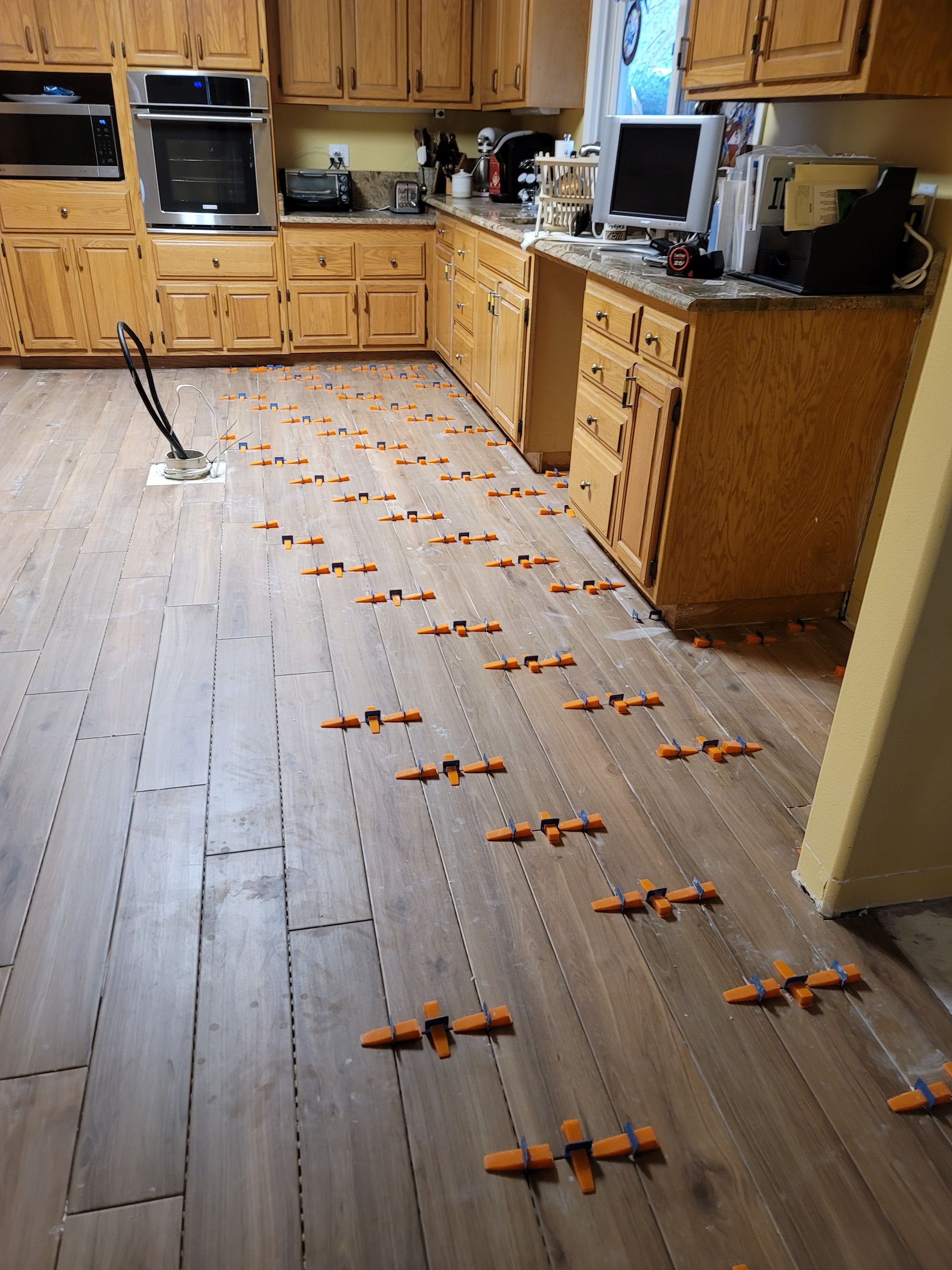 Kitchen floor lined with many small orange and black toy drones leading to cabinets and appliances