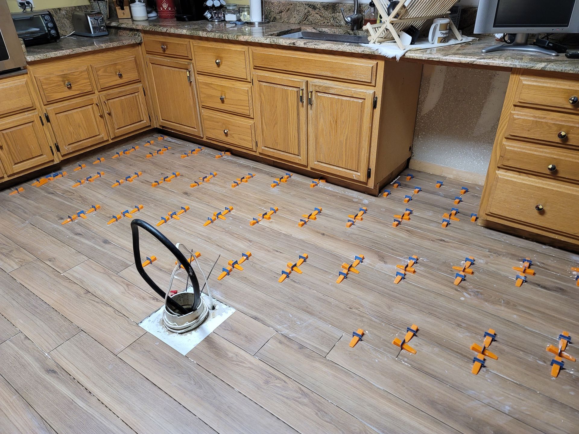 Kitchen floor with orange markings and a small device in the foreground near wooden cabinets