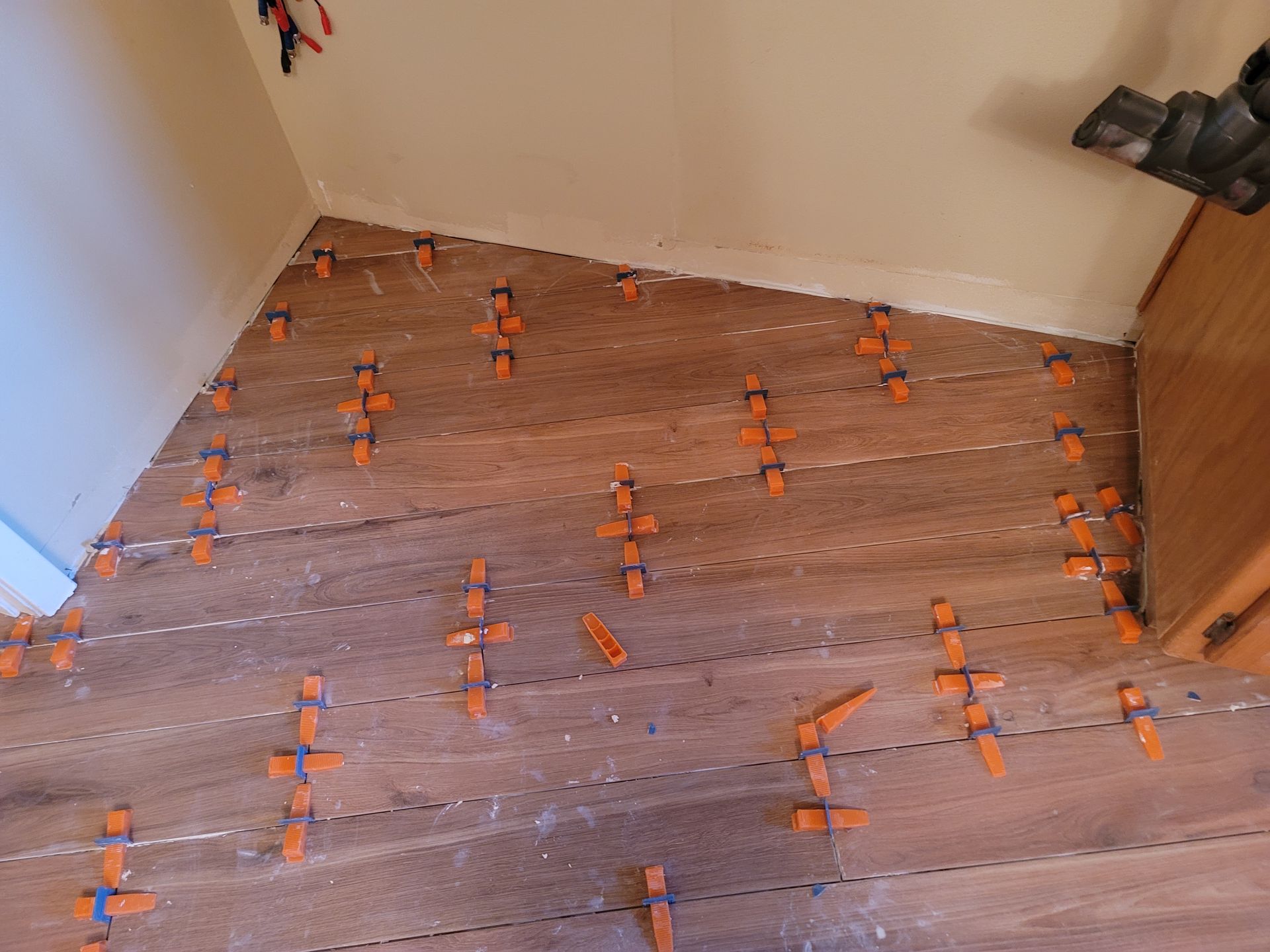 Wooden staircase under renovation with orange tile spacers and leveling clips on each step