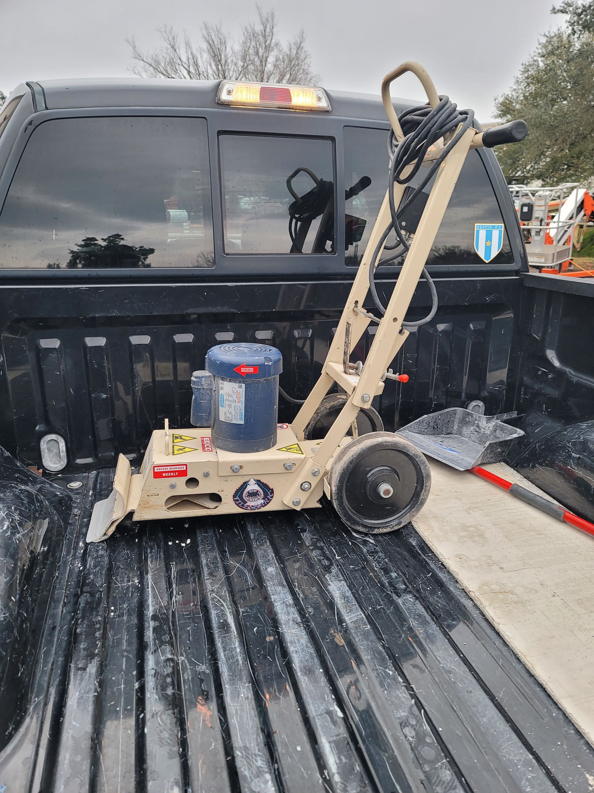 Wheelbarrow-like cart with a blue bucket in a black pickup truck bed on a snowy day