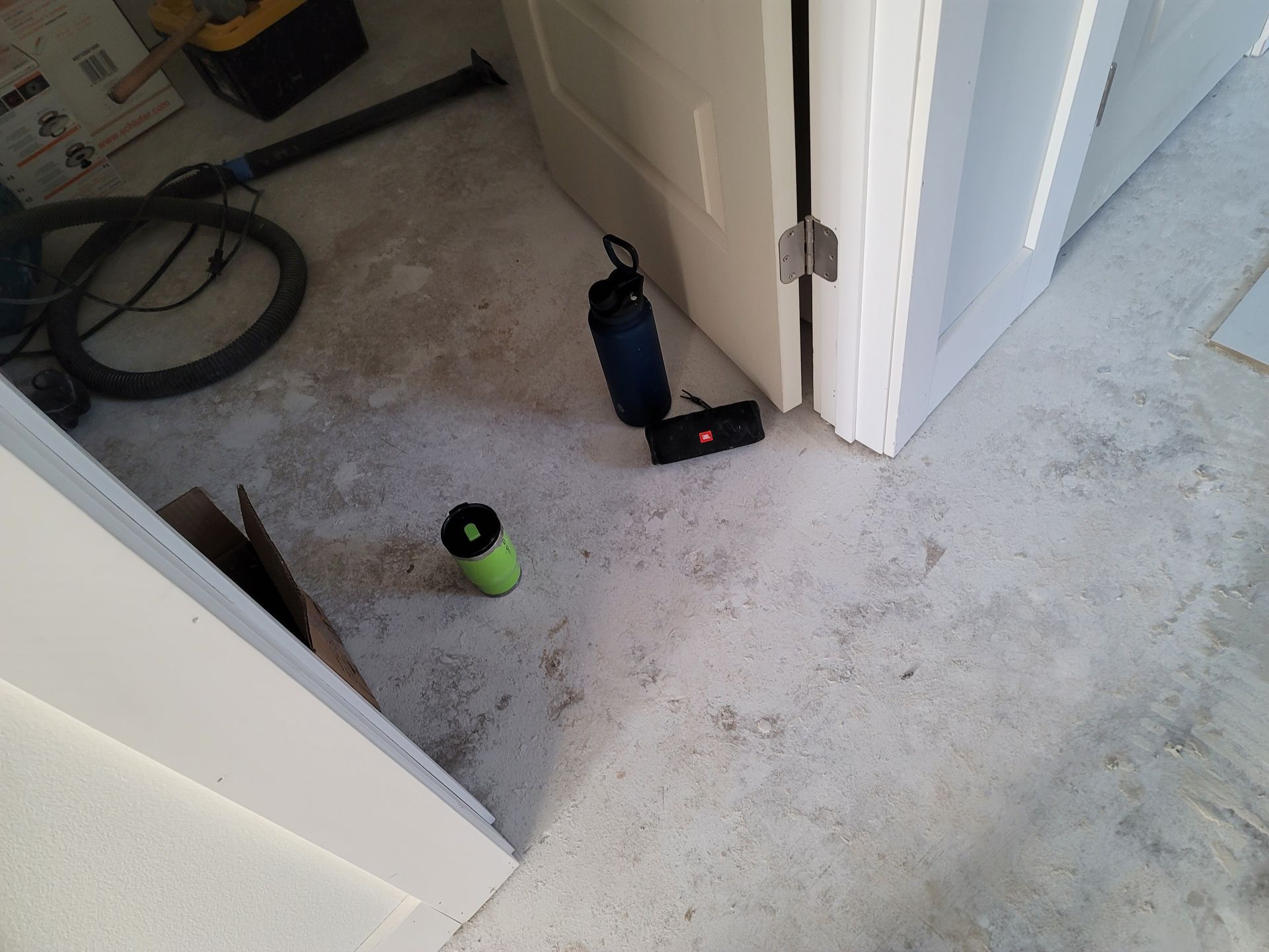Carpeted hallway with an open door, a green cup, and a blue bottle near the wall