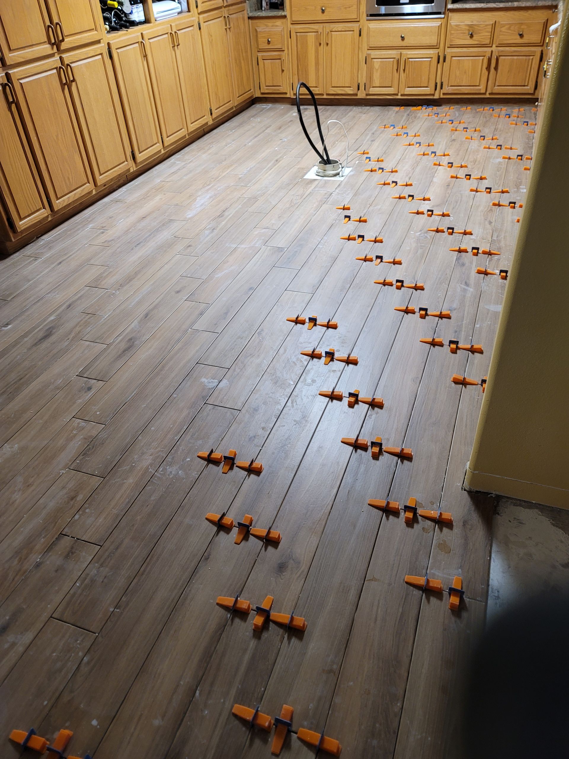 Kitchen floor with many orange snap traps and a broom near the back cabinets