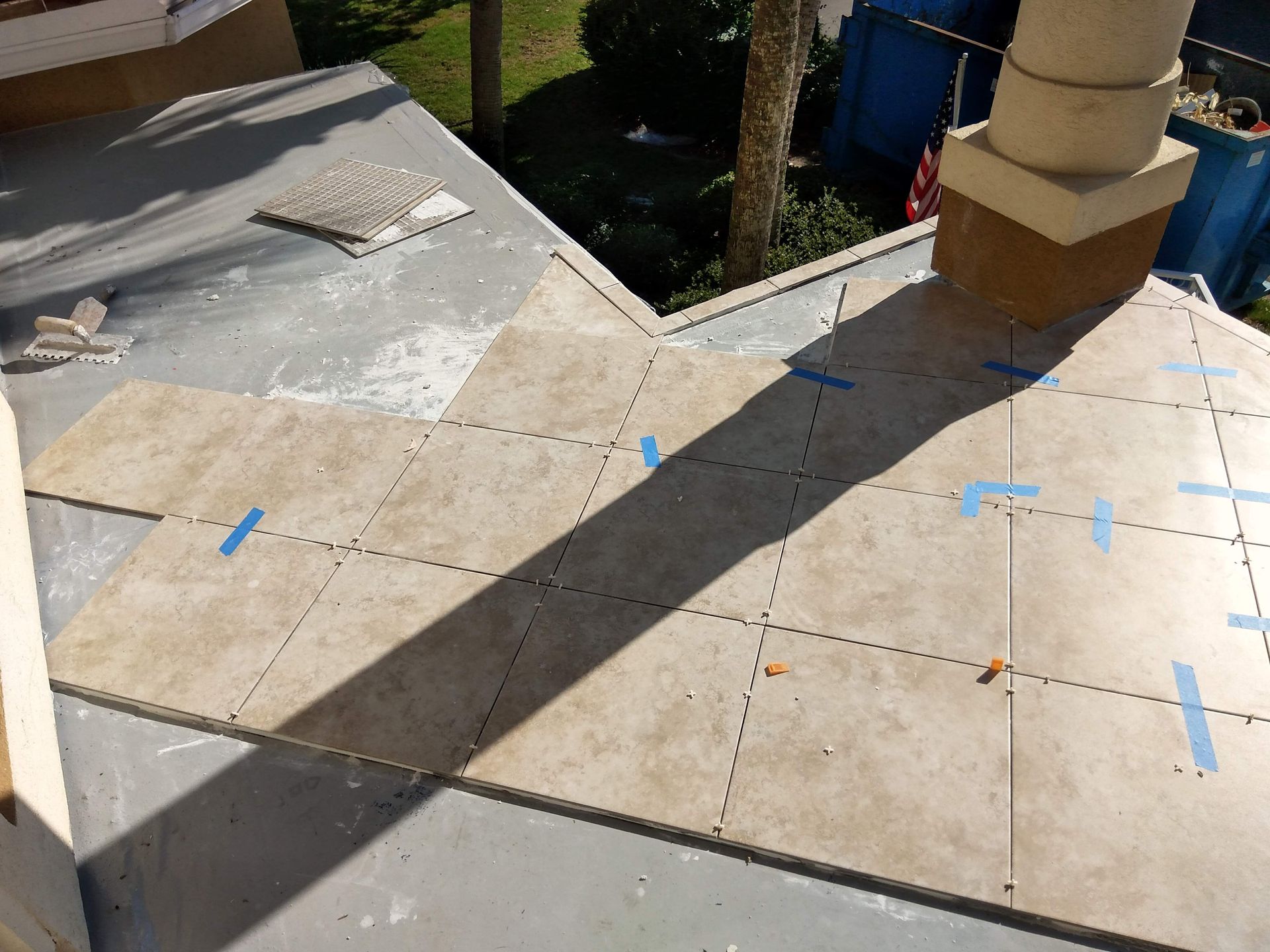 Partially tiled rooftop with blue tape markings and a large chimney shadow