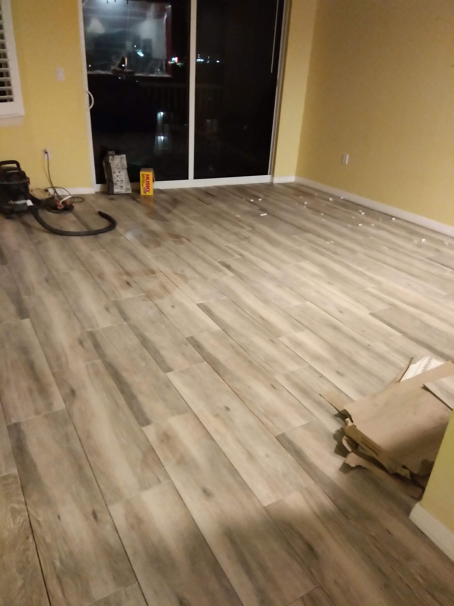Empty room with light wood flooring, yellow walls, and a sliding glass door at the back.