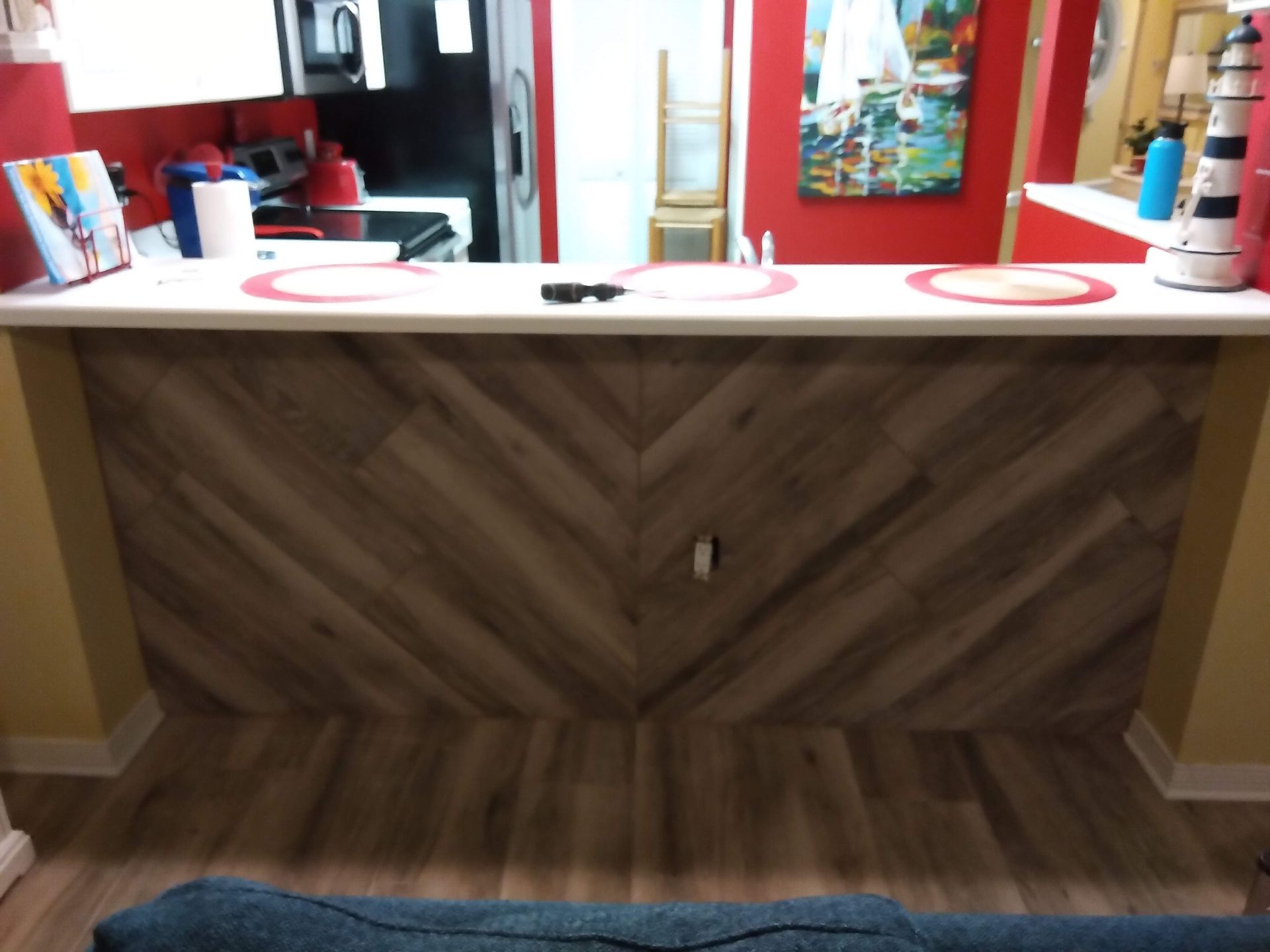 White countertop vanity with round sinks, red accents, and wood herringbone cabinet front in a salon/bathroom setting