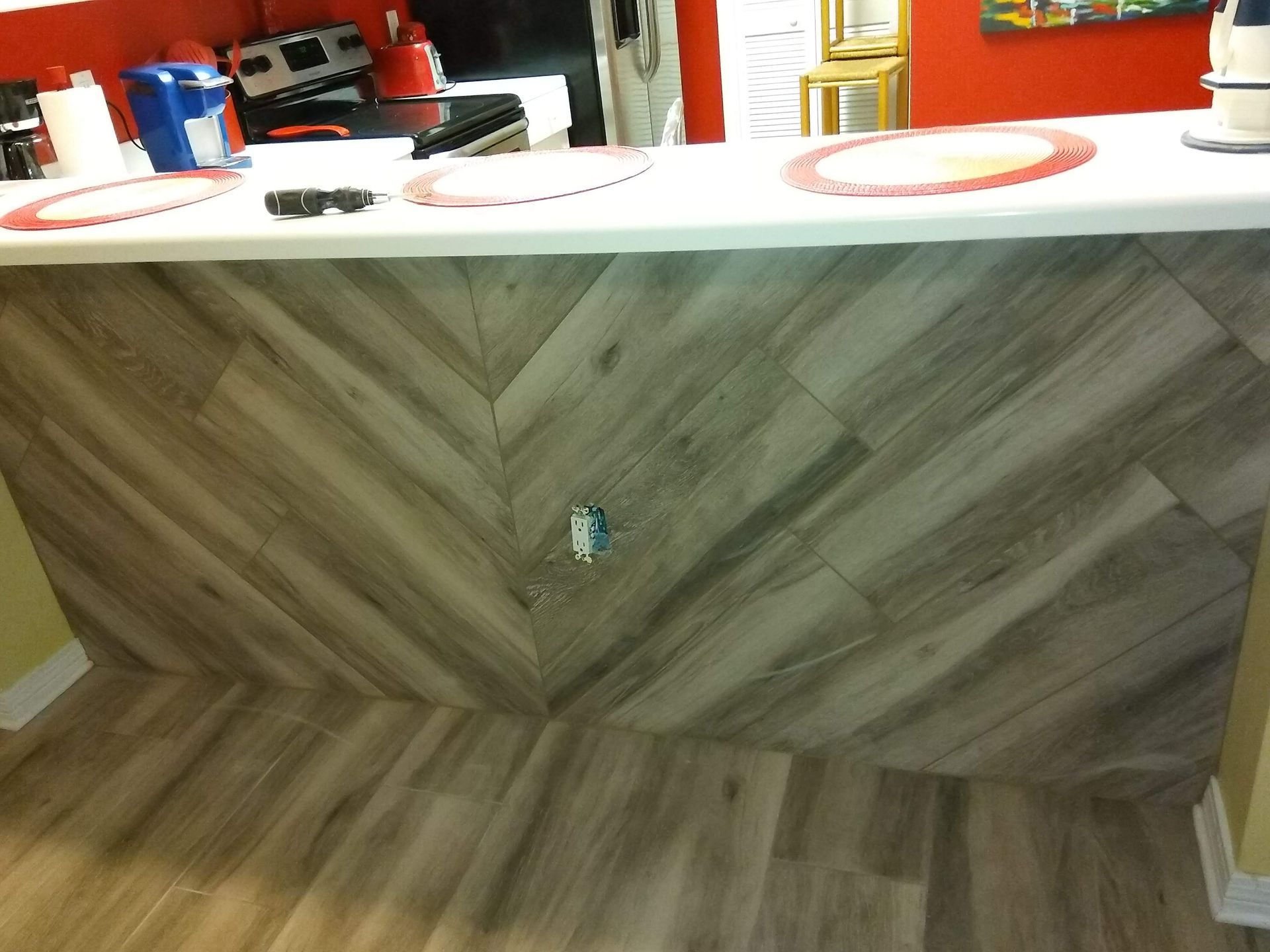 Wood-paneled bar counter with a white countertop and red items on top.