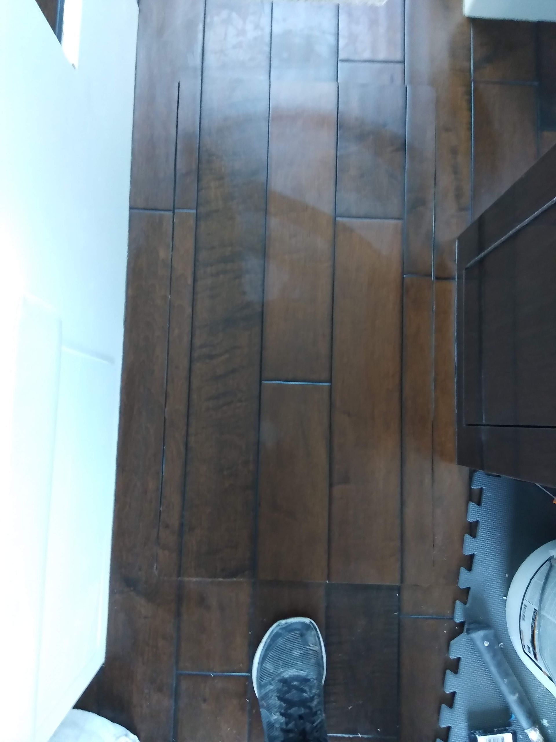 Wooden floor with a sneaker at the bottom edge and a white wall on the left.