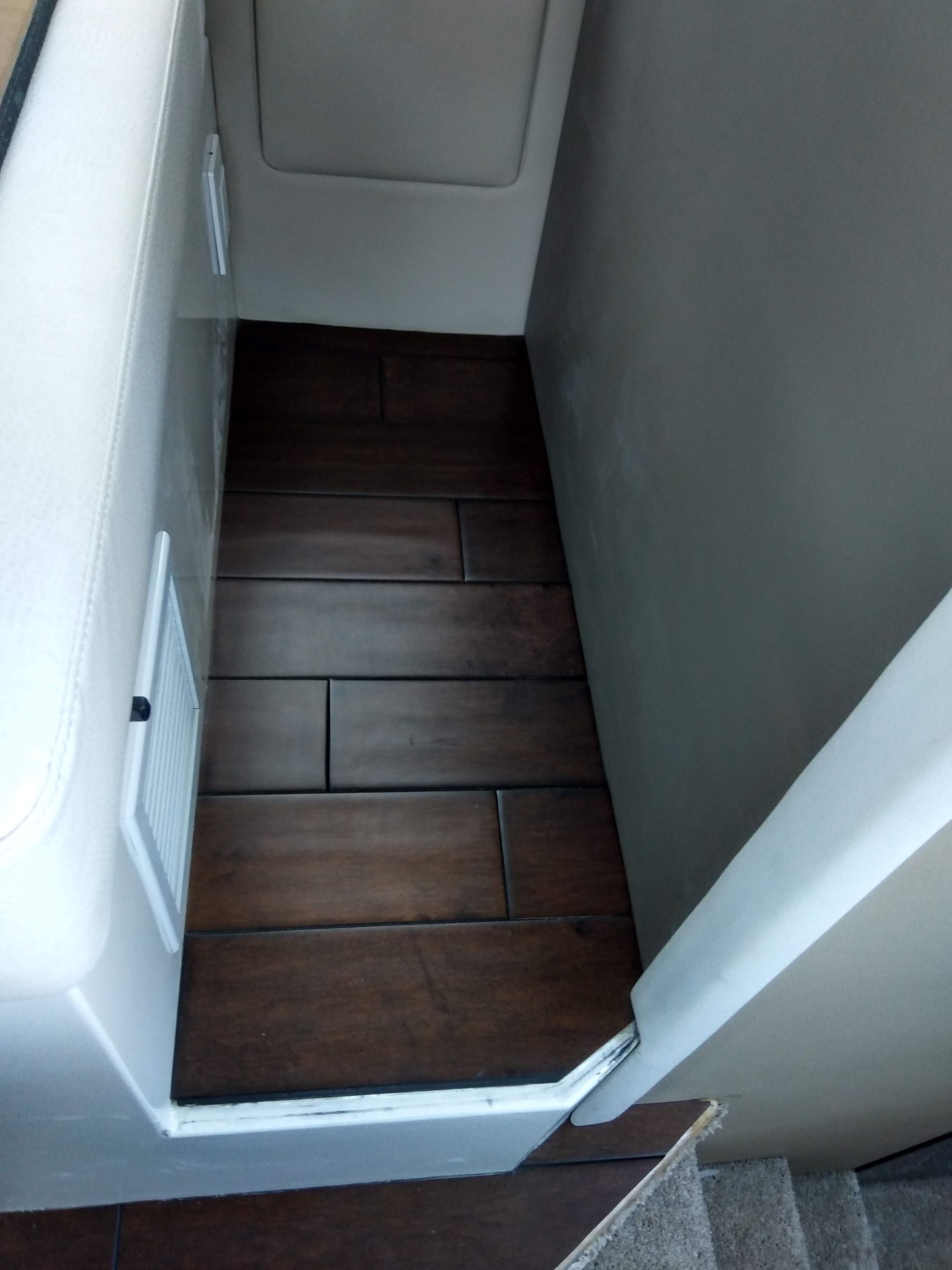 Narrow hallway with dark wood floor and white walls, viewed from above.