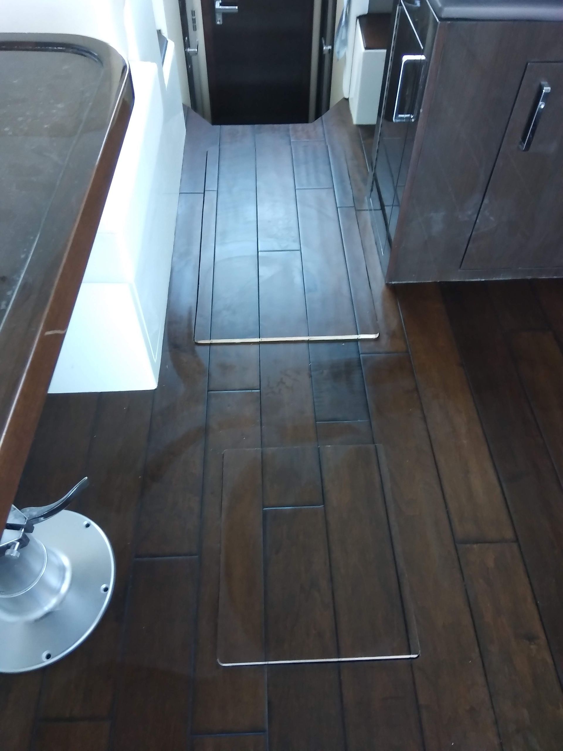 Wooden hallway floor with loose floorboards and a table and cabinet on either side