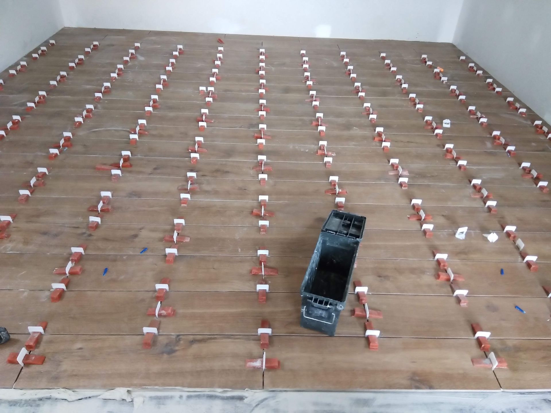 Rows of small red-and-white markers on a floor with a black device near the center.