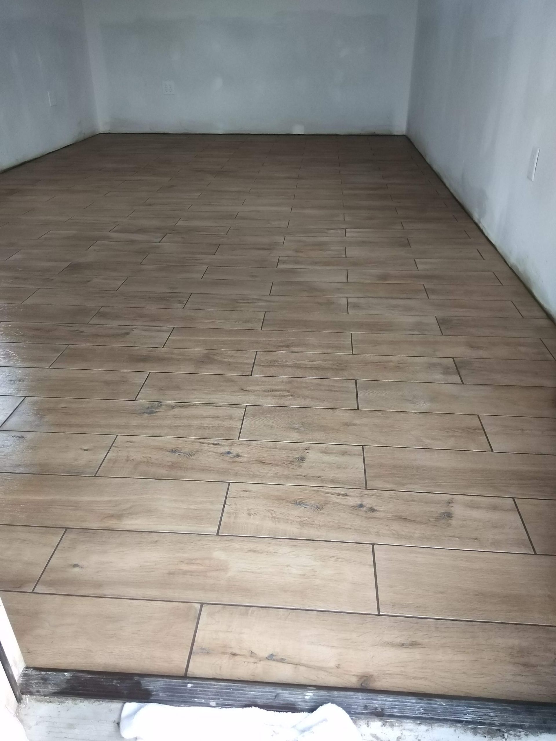 Empty room with unfinished wooden floor and white walls
