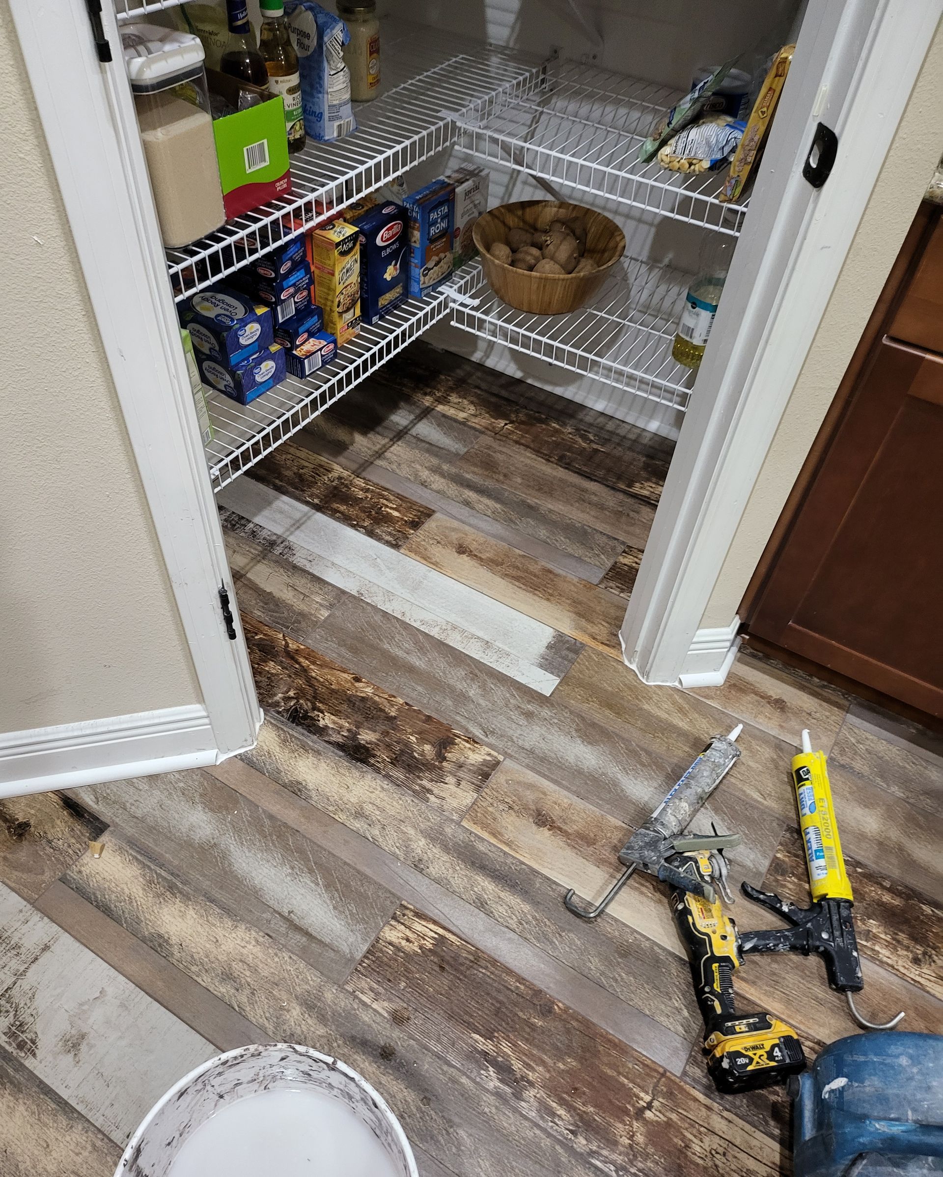 Pantry floor with damaged linoleum and tools on the ground, suggesting ongoing repair work.