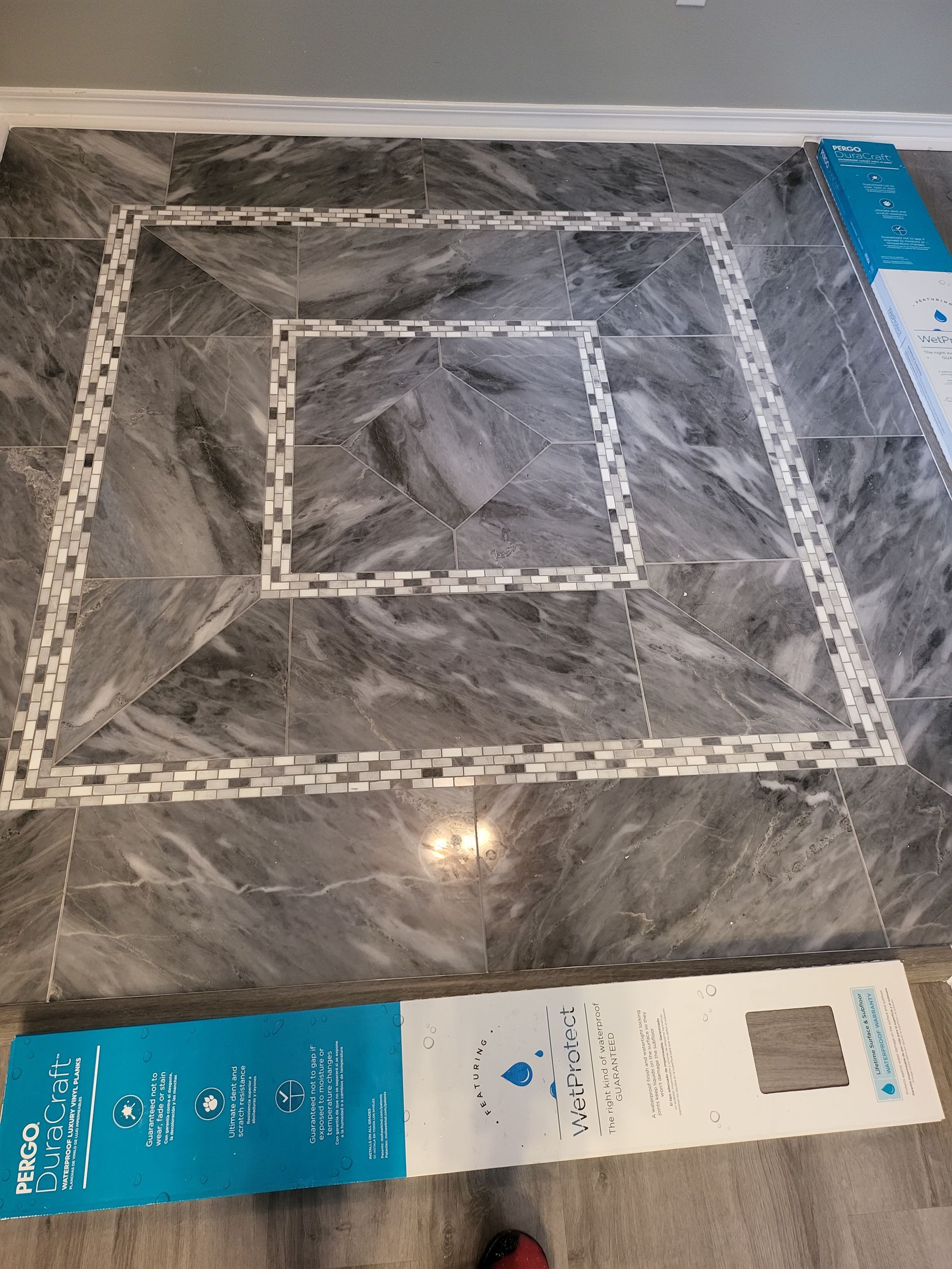 Gray marble-patterned square tabletop with concentric square trim and product labels along the bottom edge.