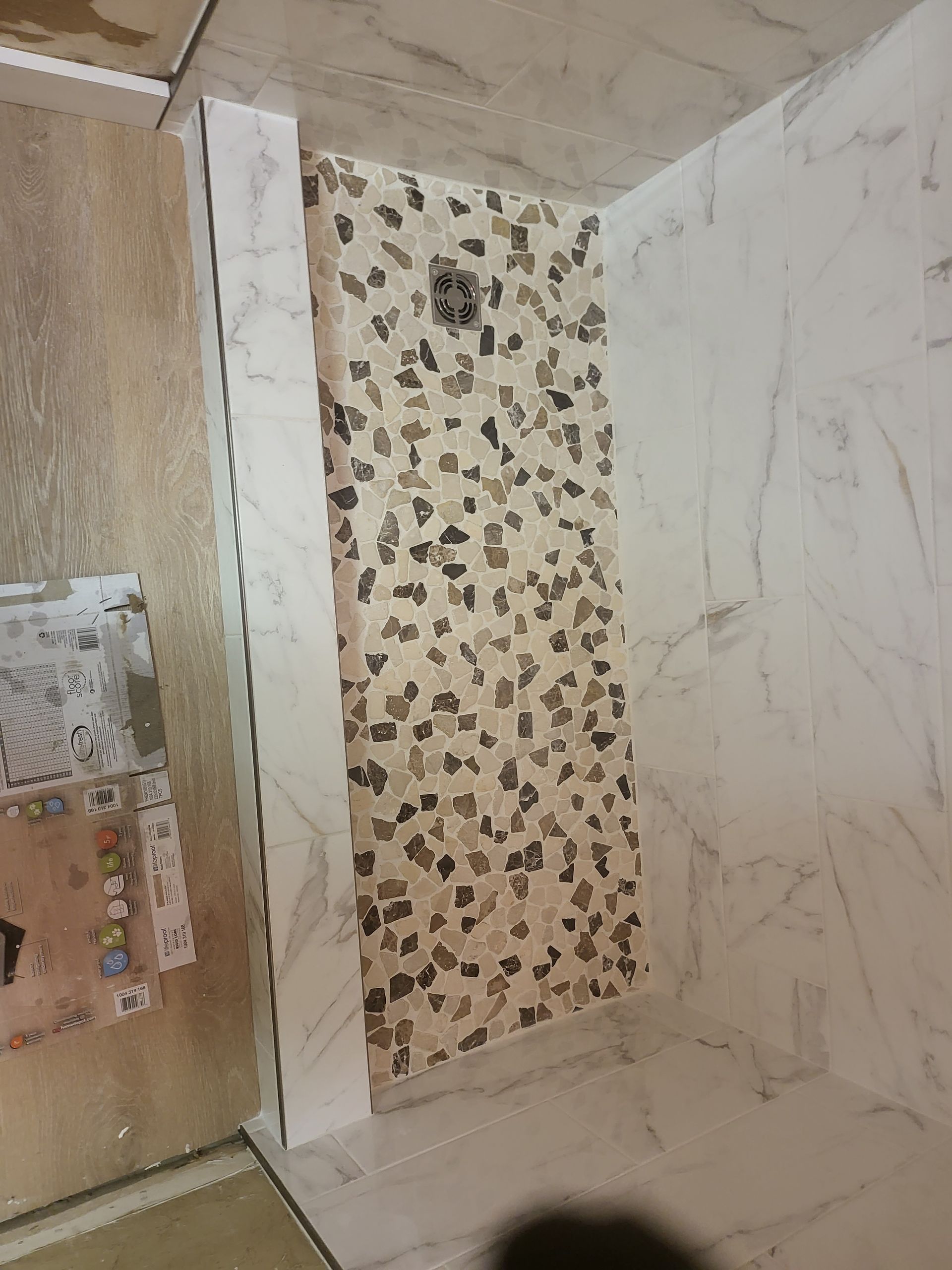 Bathroom shower with marble-look walls and a beige floral accent tile panel