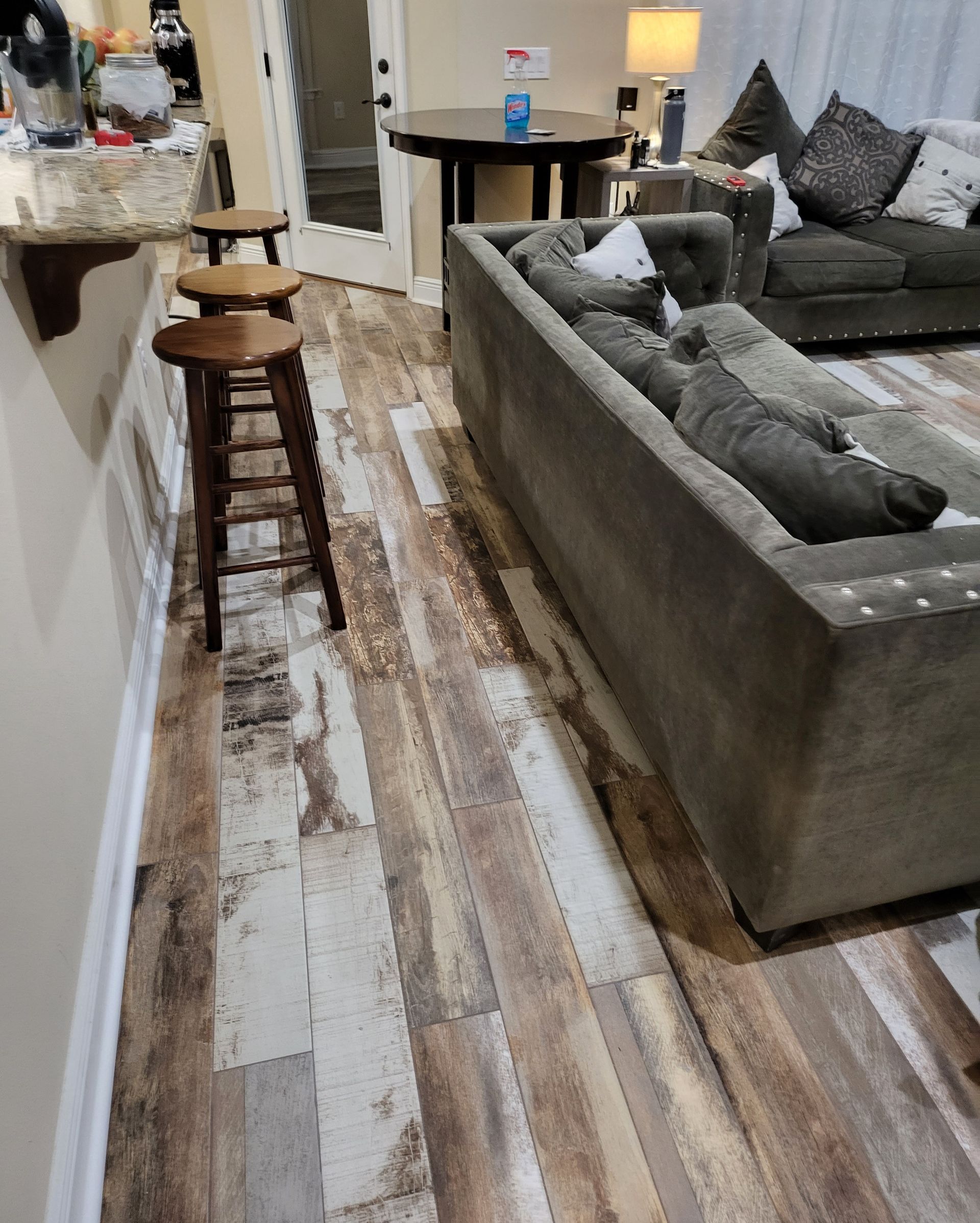 Modern living room with gray sectional sofa, stools, and striped rug on wood floor