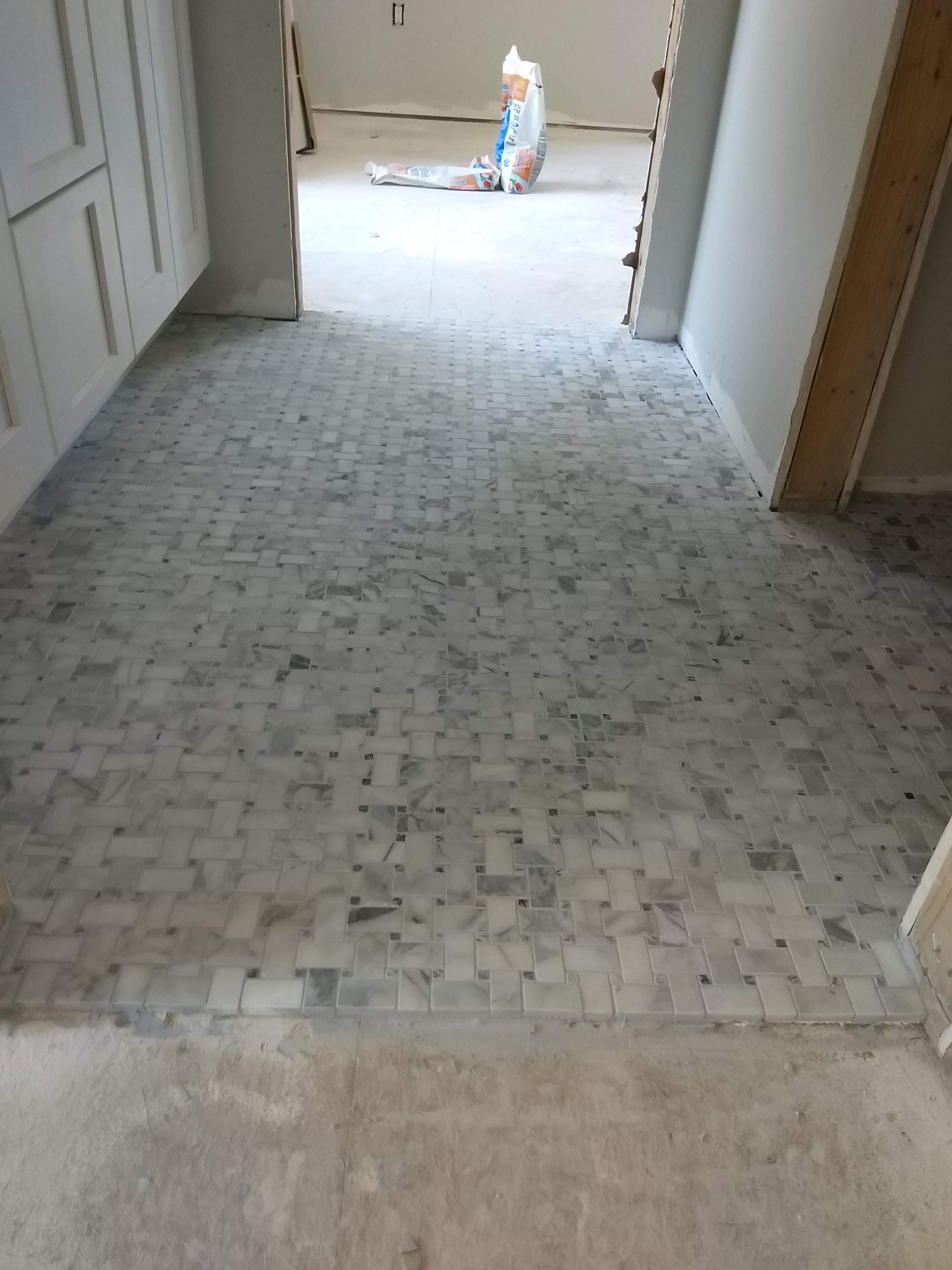 Narrow hallway with light tile floor and a bag of tools or supplies at the far end