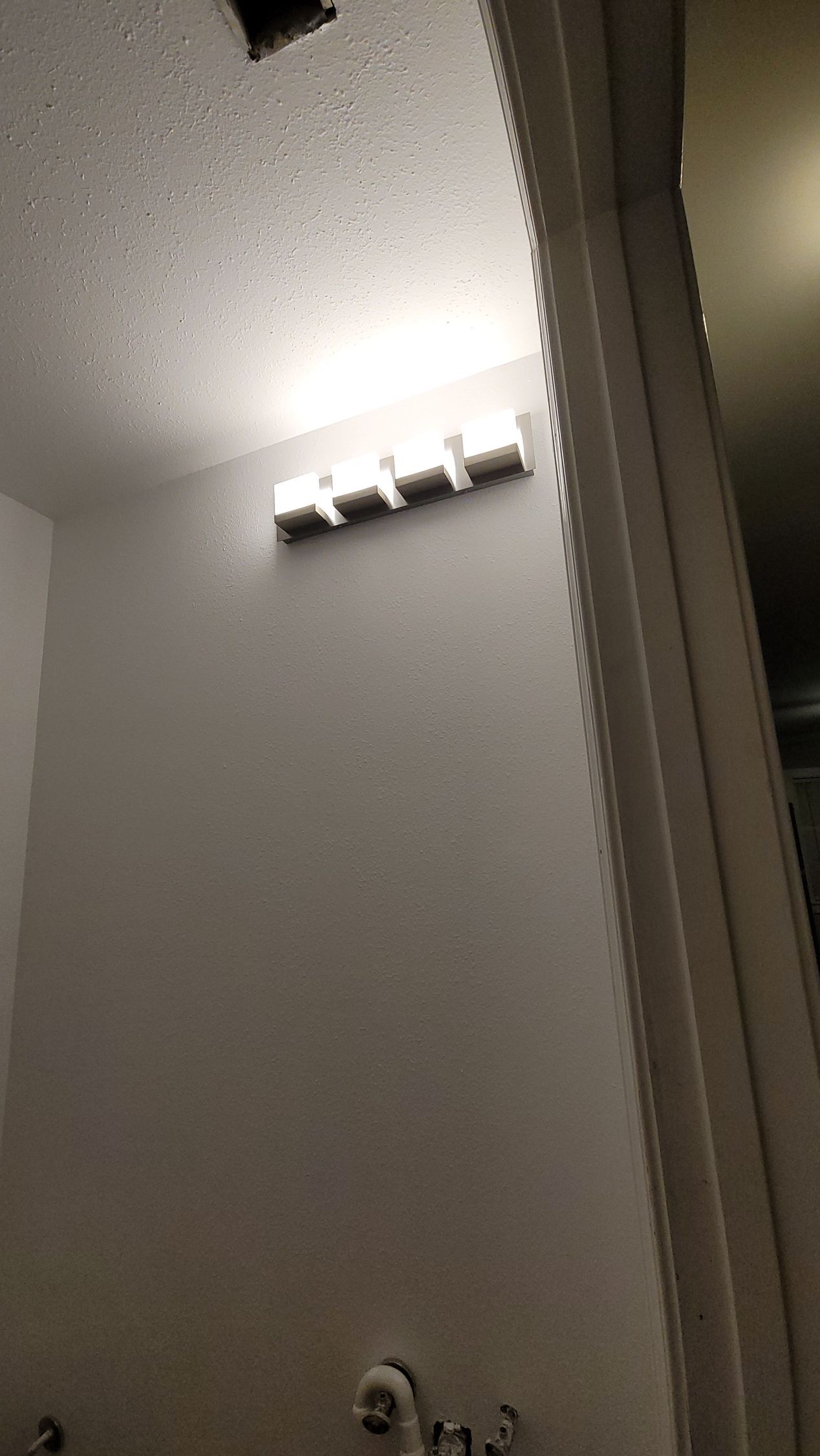 Bright bathroom ceiling light above a gray wall and door frame
