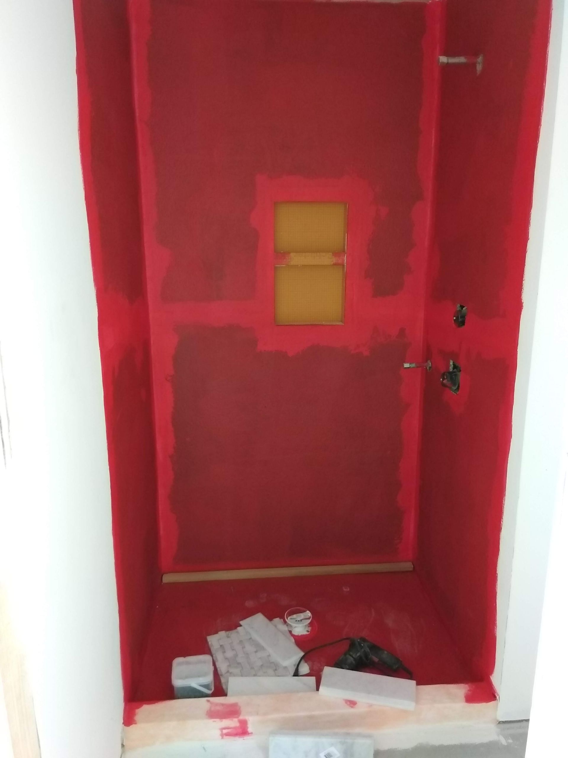 Red-painted hallway or closet with a small window and debris scattered on the floor