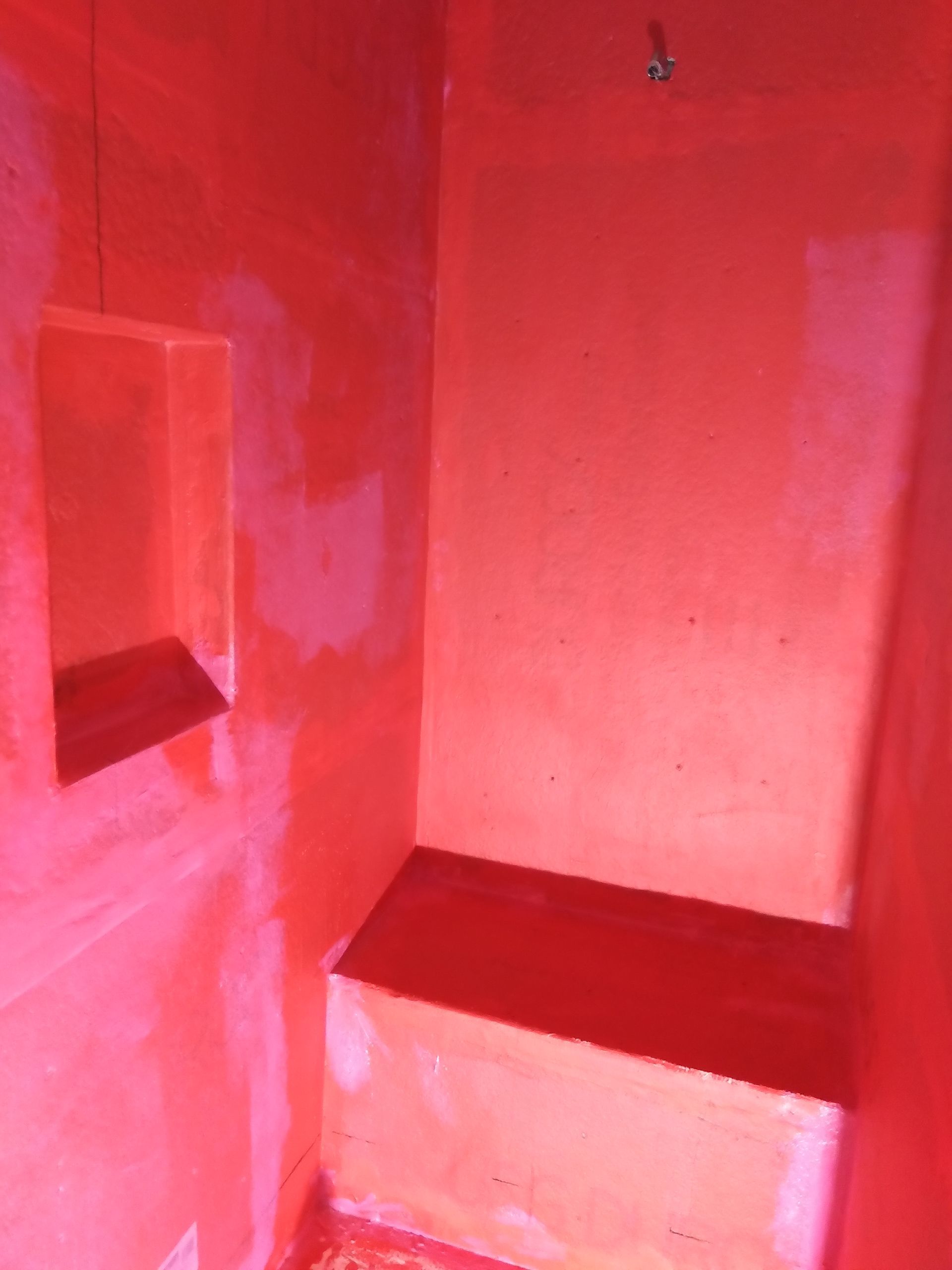 Small red-painted alcove with a built-in bench and window opening.