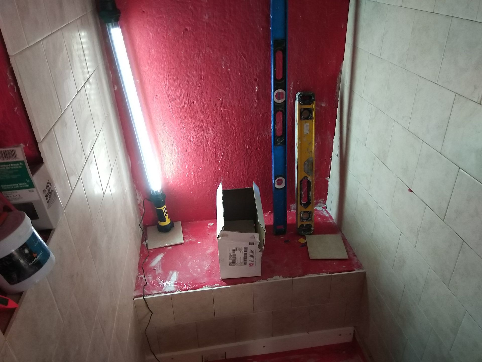 Three spirit levels and a flashlight on a red windowsill by a curtained window.