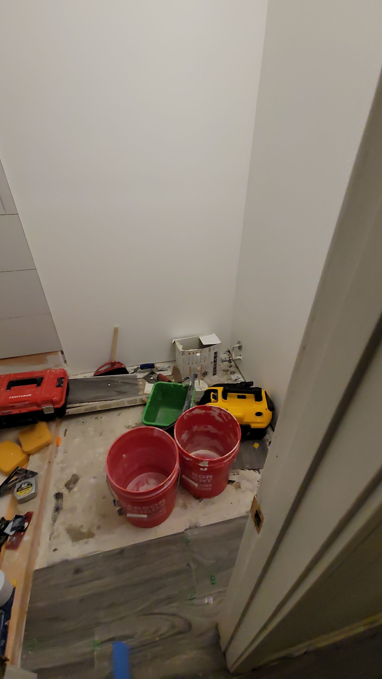 Toys and red plastic buckets scattered on a stair landing by a white wall