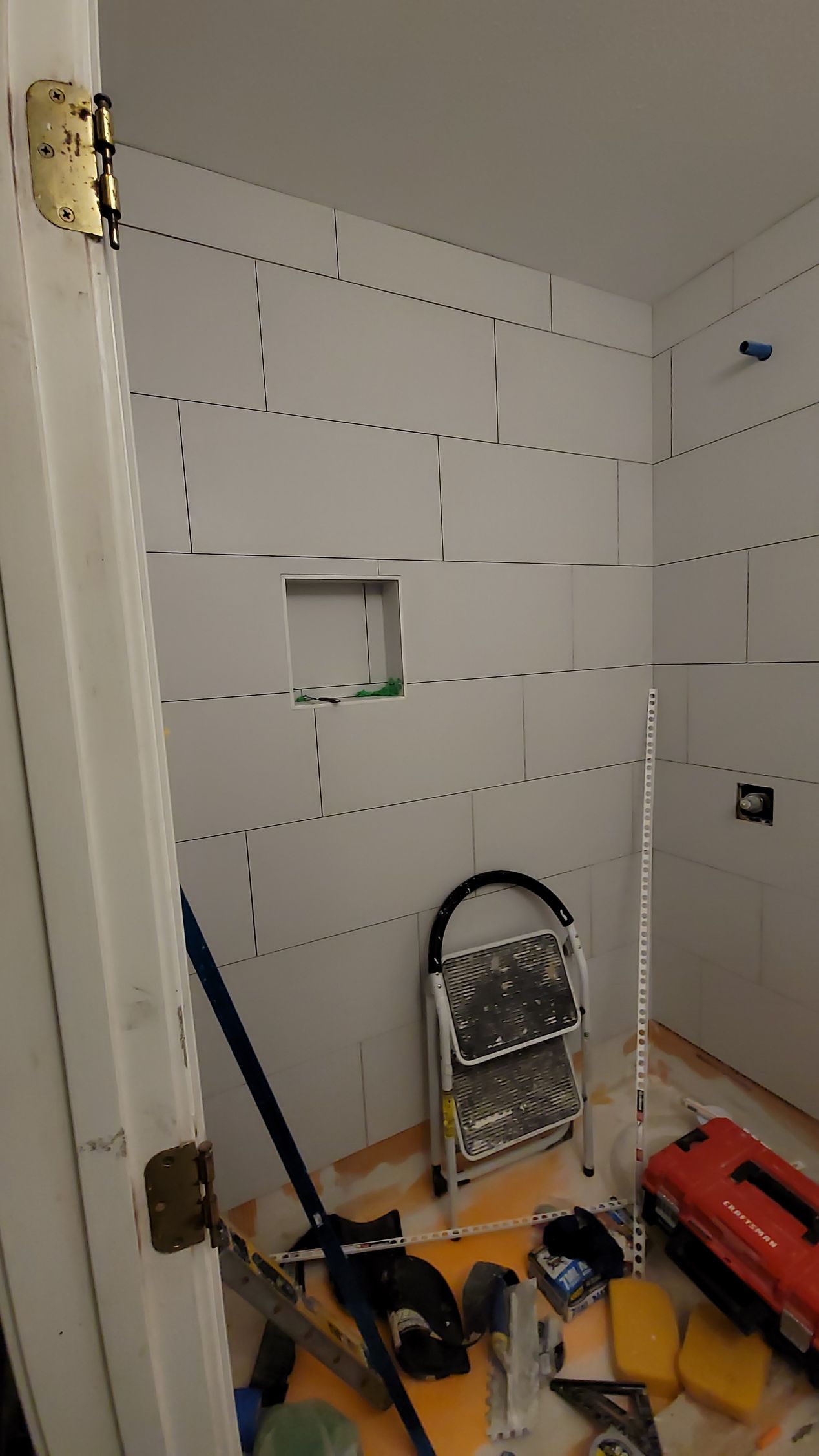 Partially finished room with drywall, tools, and a stepladder on the floor.
