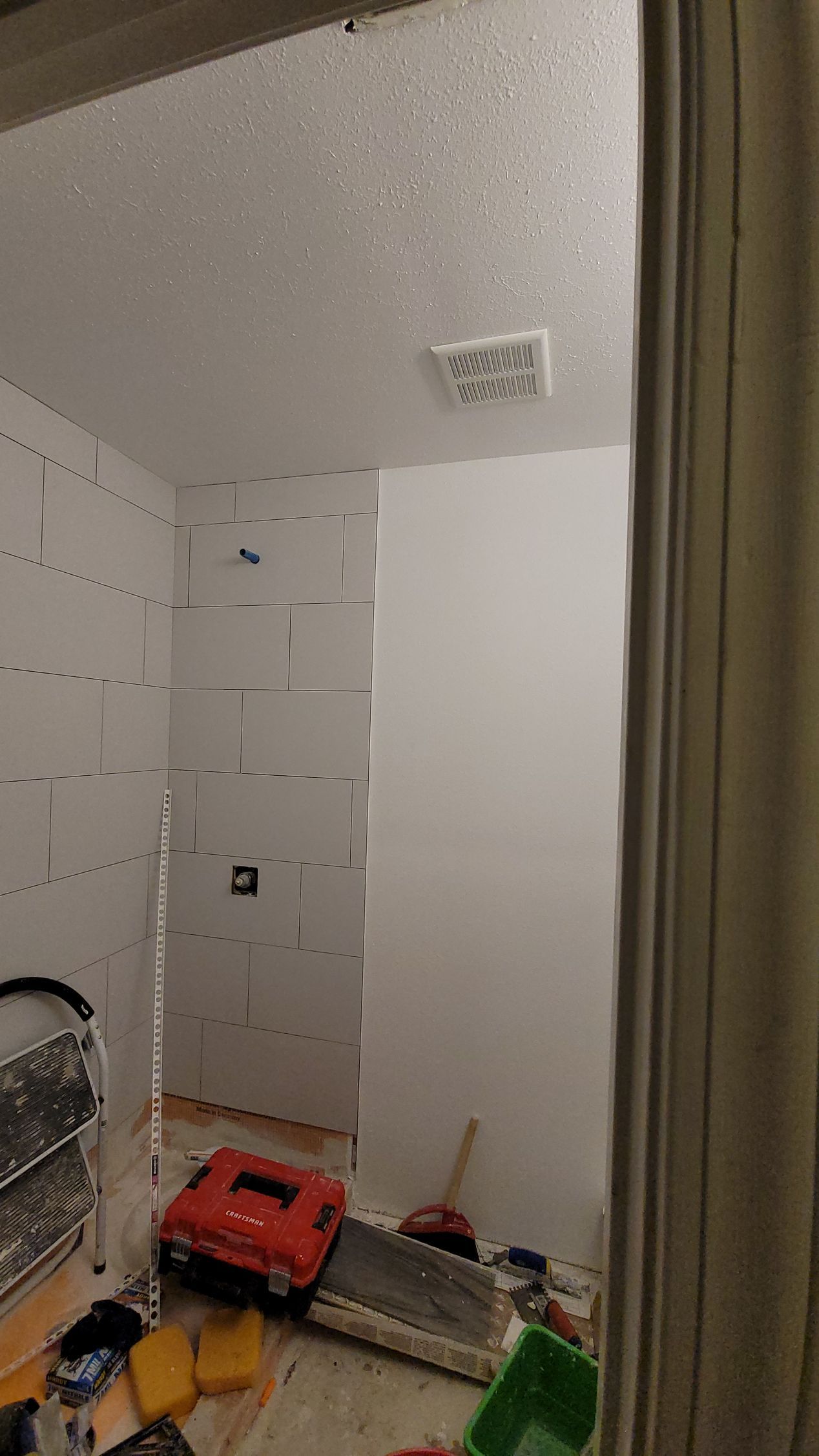 Small utility room with white walls, a ceiling vent, and cleaning tools and bins scattered on the floor.