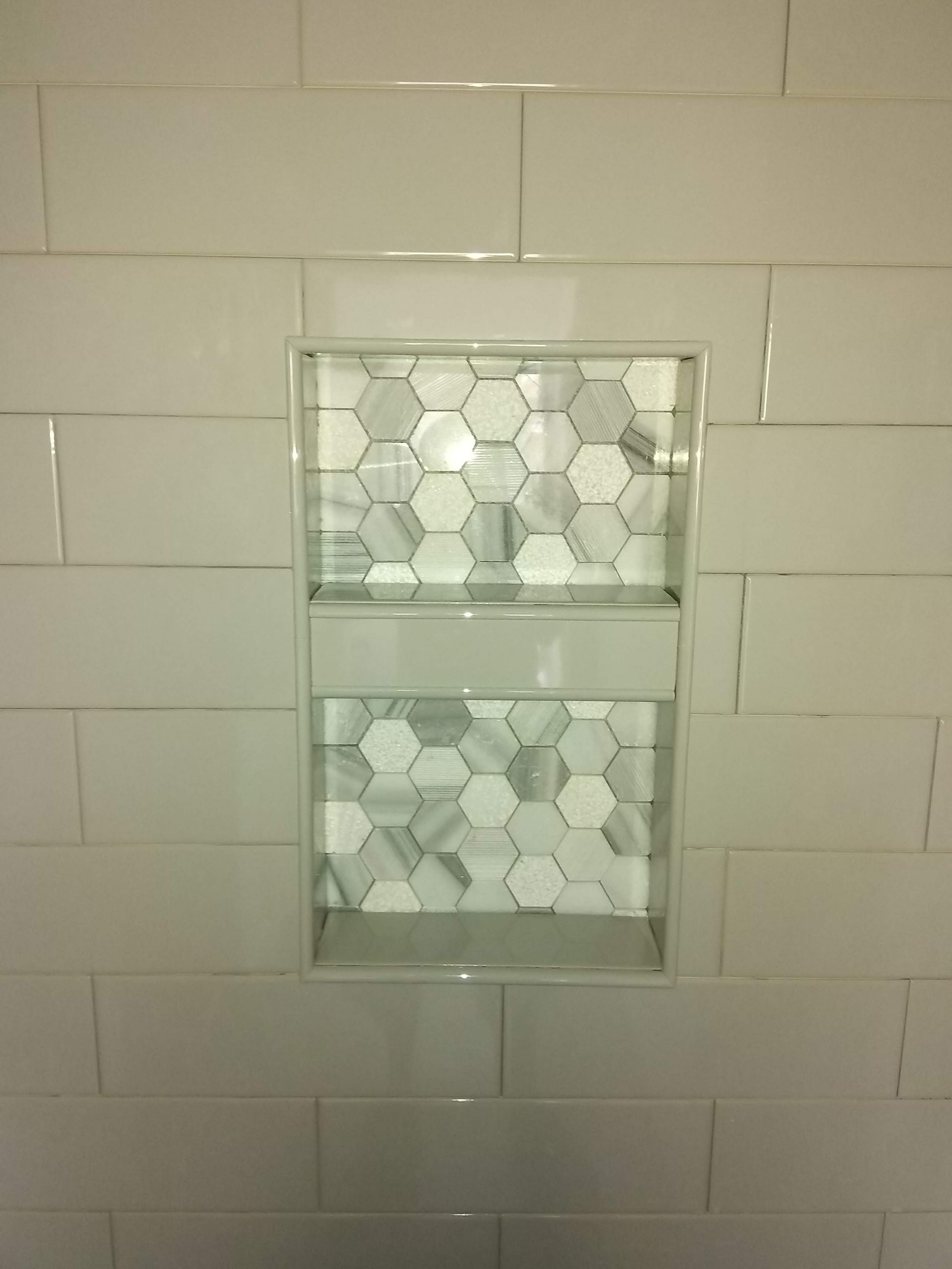 Small built-in bathroom mirror cabinet set into white subway tile wall.