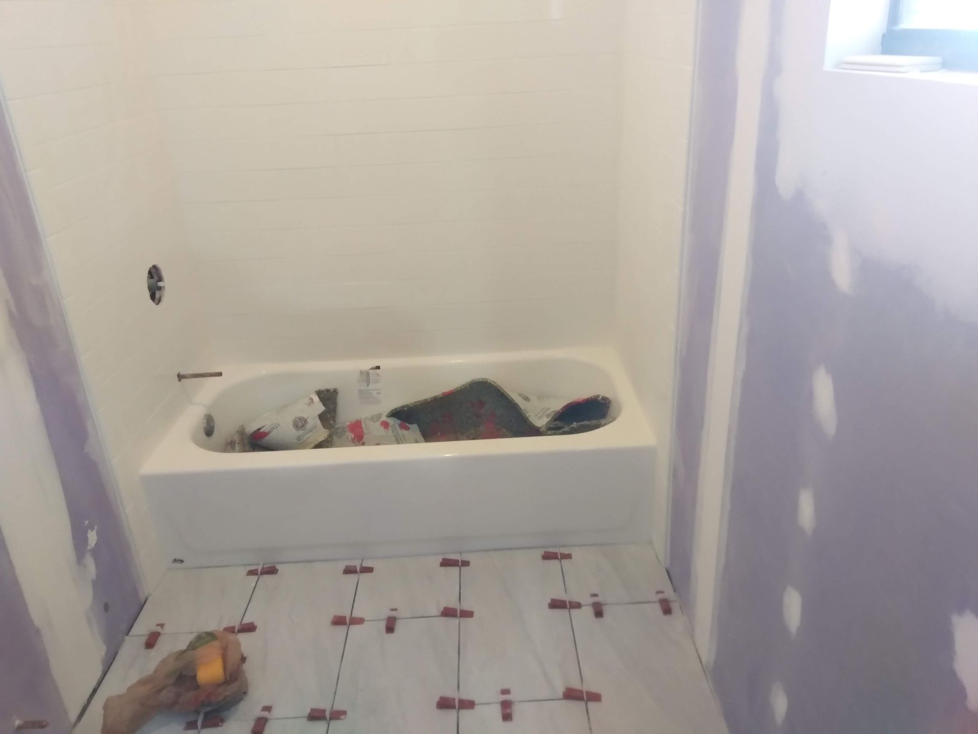 Bathroom under renovation with unfinished walls, a white tub, and exposed plumbing fixtures.