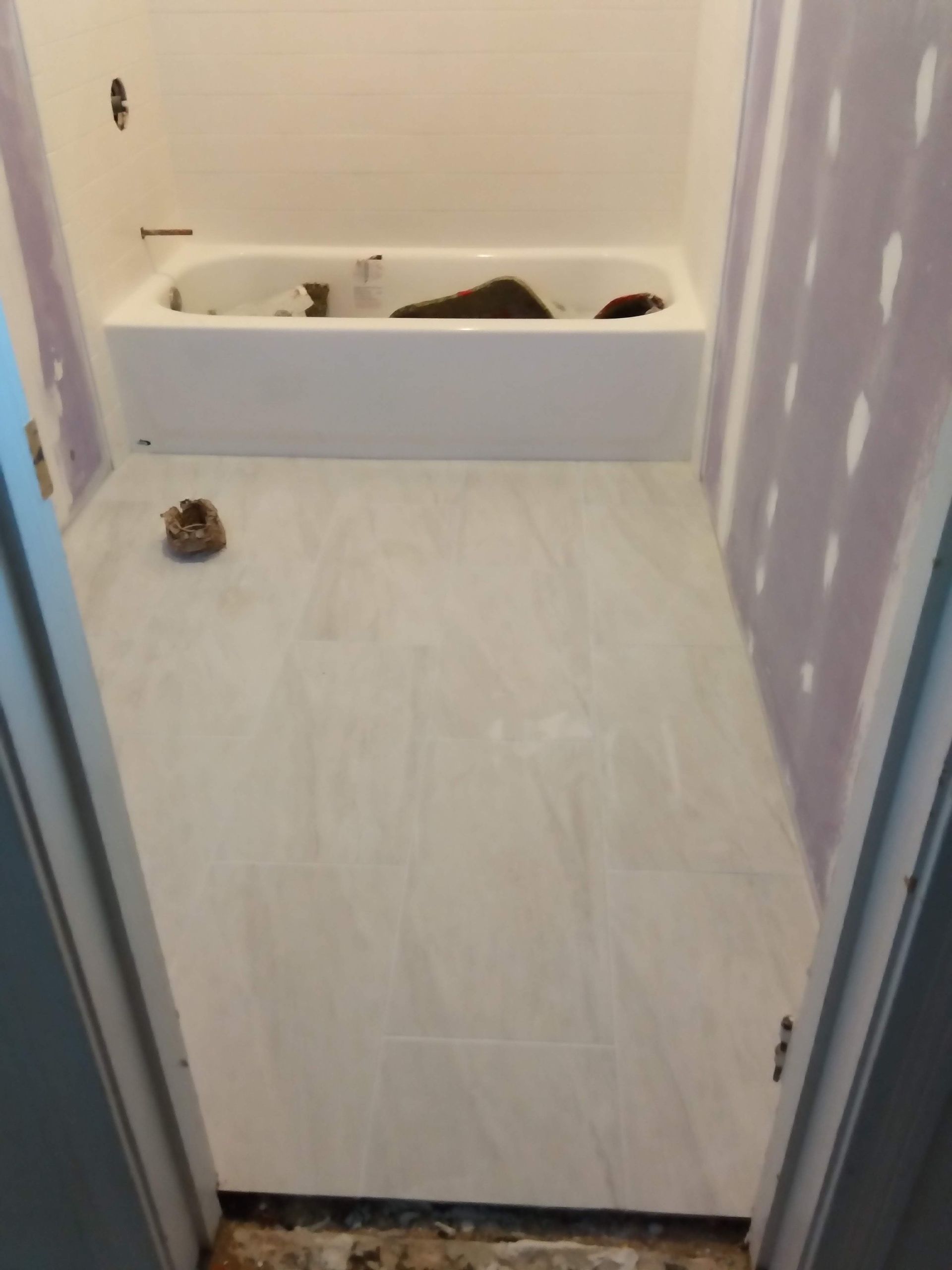 Bathroom with a white tub, lavender walls, and a dark floor mat near the doorway.