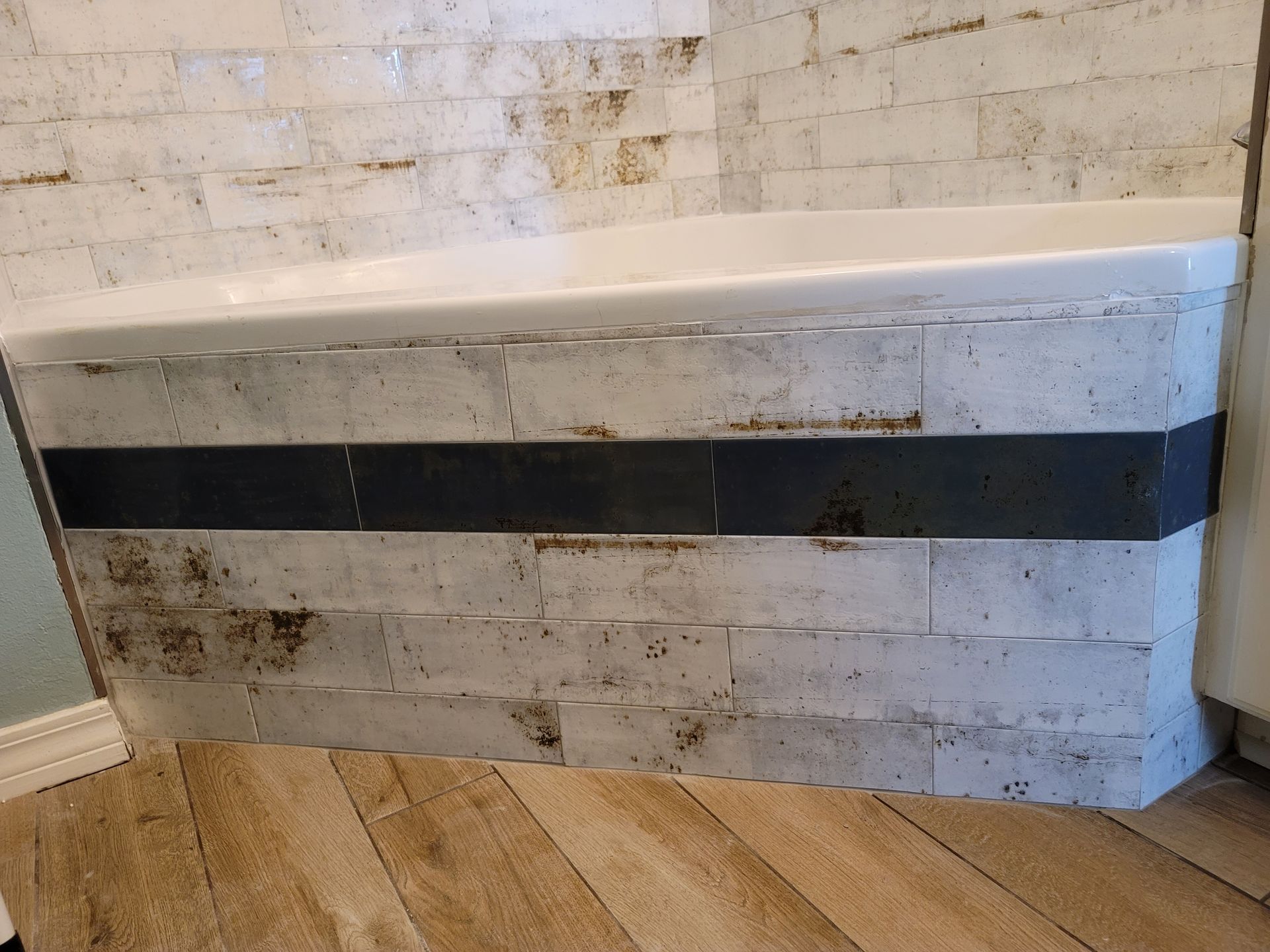Curved white bench with black stripe against a weathered white brick wall and wood floor