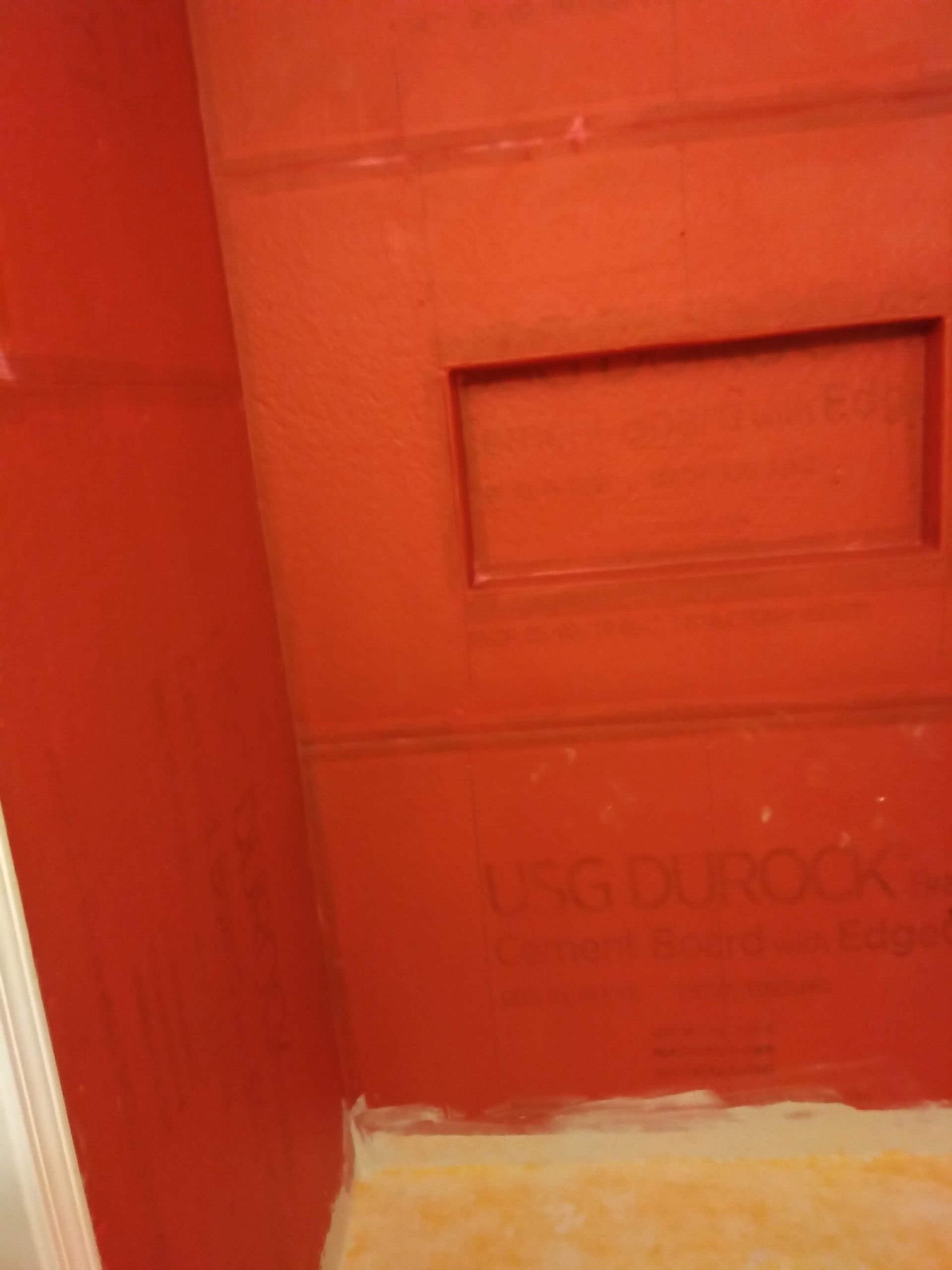 Close-up of a red/orange USPS mailbox door with a mail slot and worn paint.