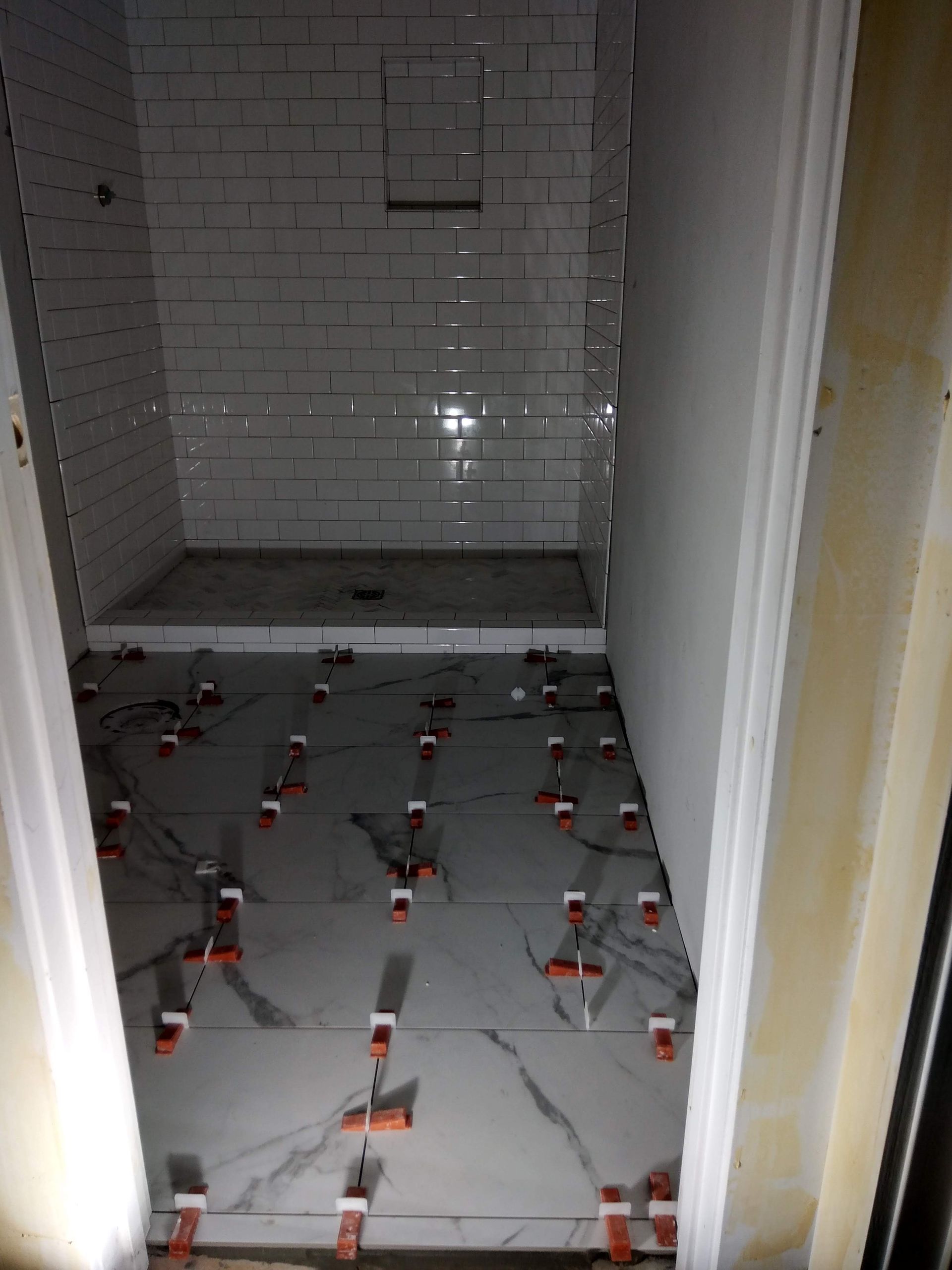 Bathroom floor covered with tile-leveling clips and spacers during renovation