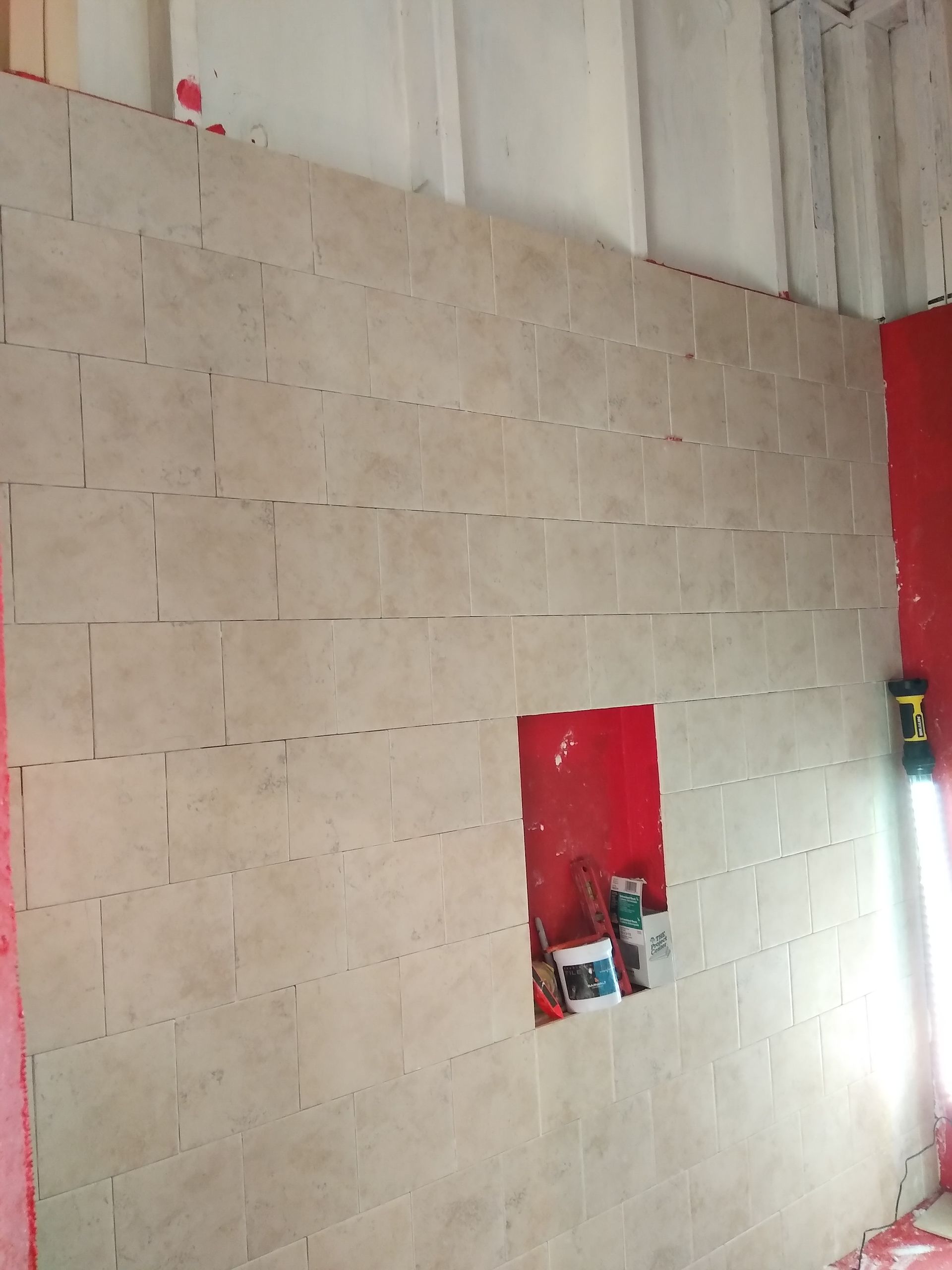Unfinished concrete block wall with a small red recessed opening and bright light at right edge