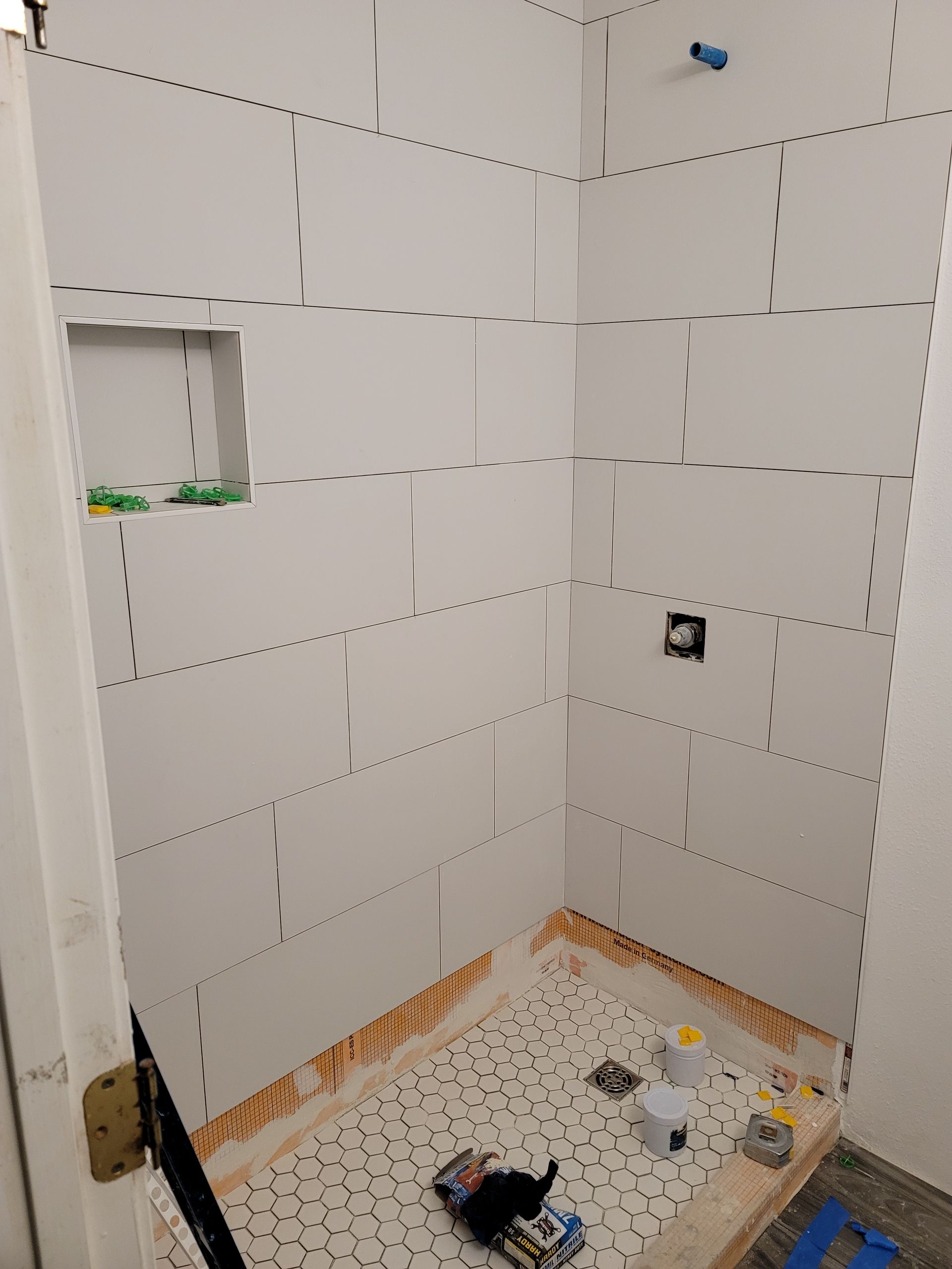 Tiled bathroom shower under renovation with tools and supplies on the floor
