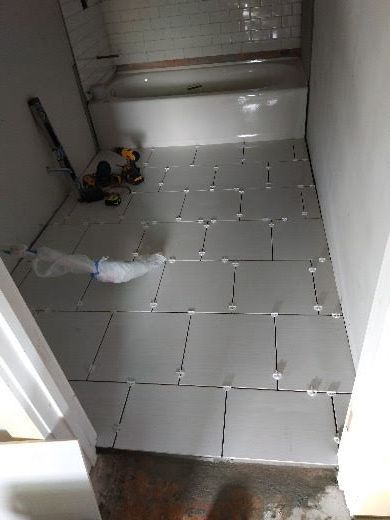 Small tiled utility room with a toy car, broom, and clutter near the back wall.