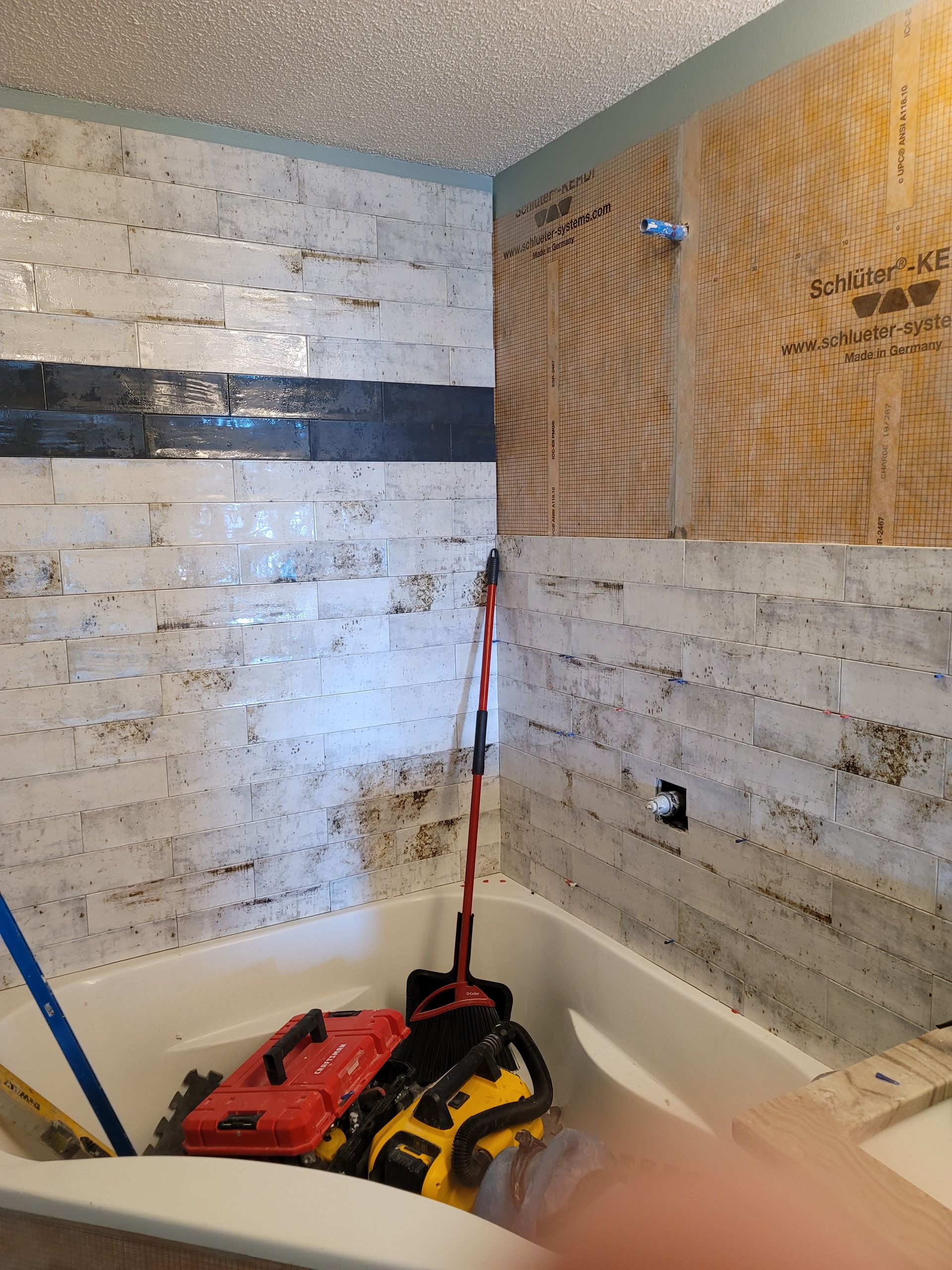 Bathroom under renovation with stacked tools and plywood covering part of the wall.