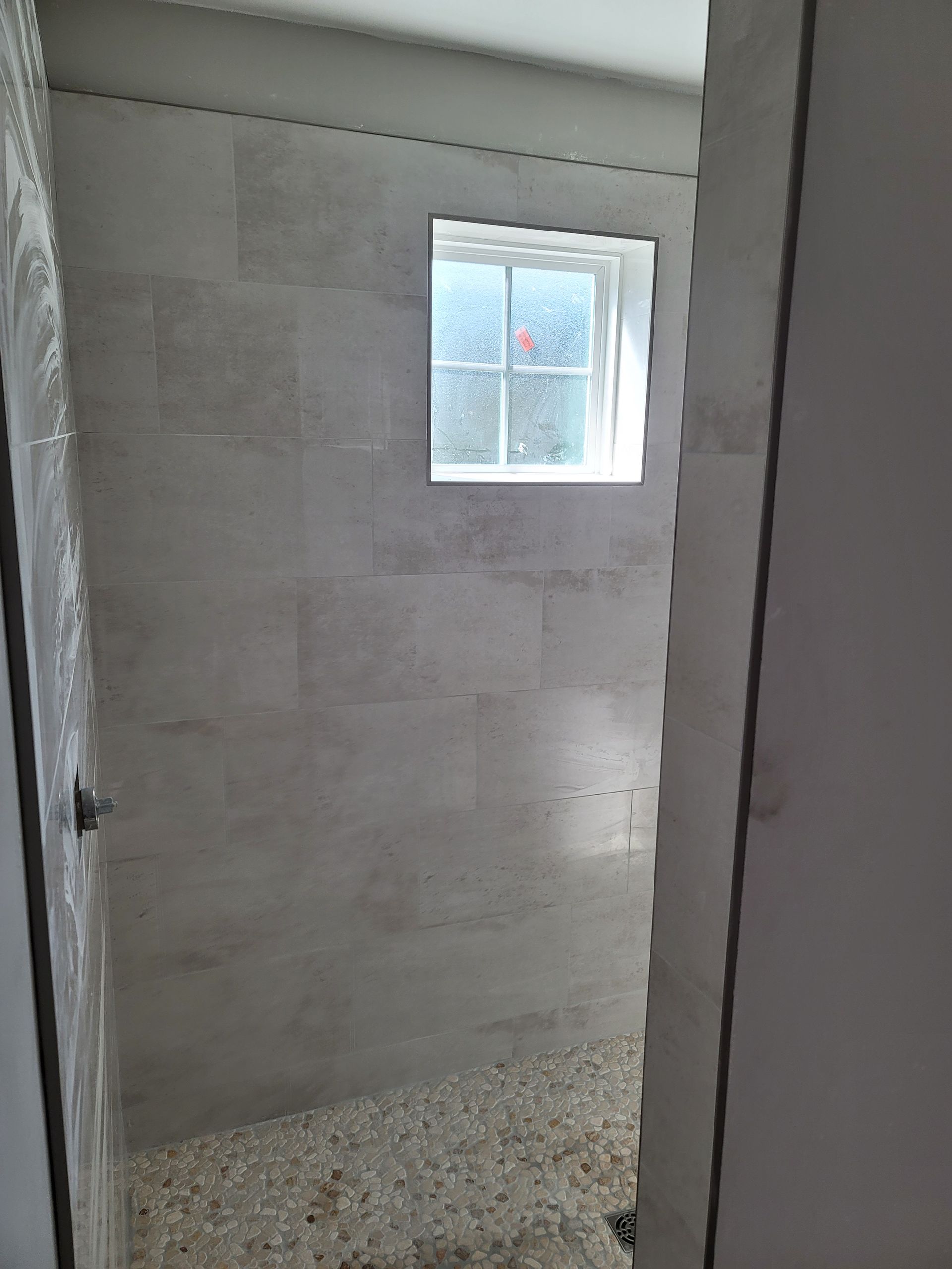 Small unfinished room with concrete walls, gravel floor, and a small window.