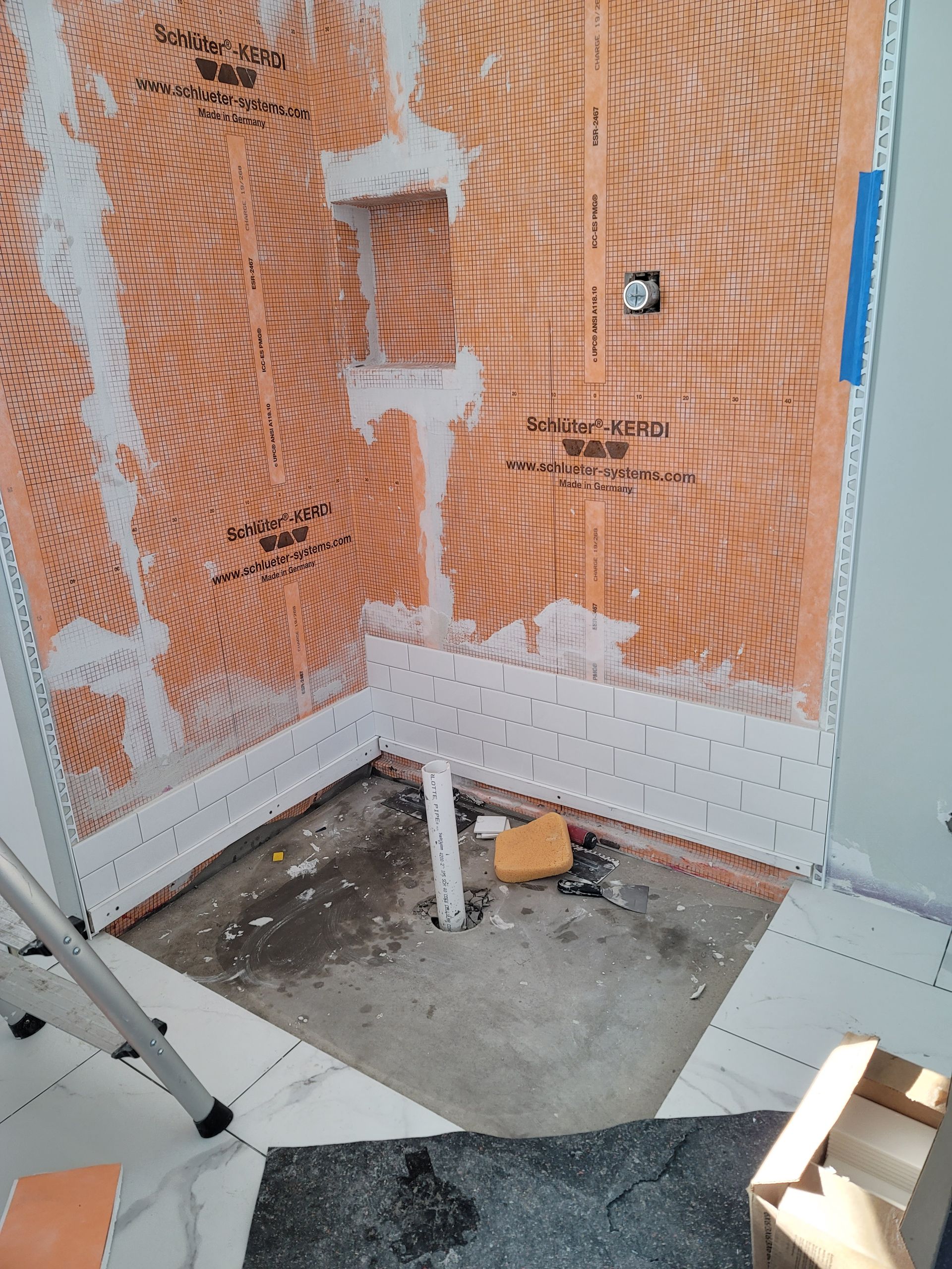 Construction area corner with orange mesh wall, white framing, and concrete floor with tools/materials.