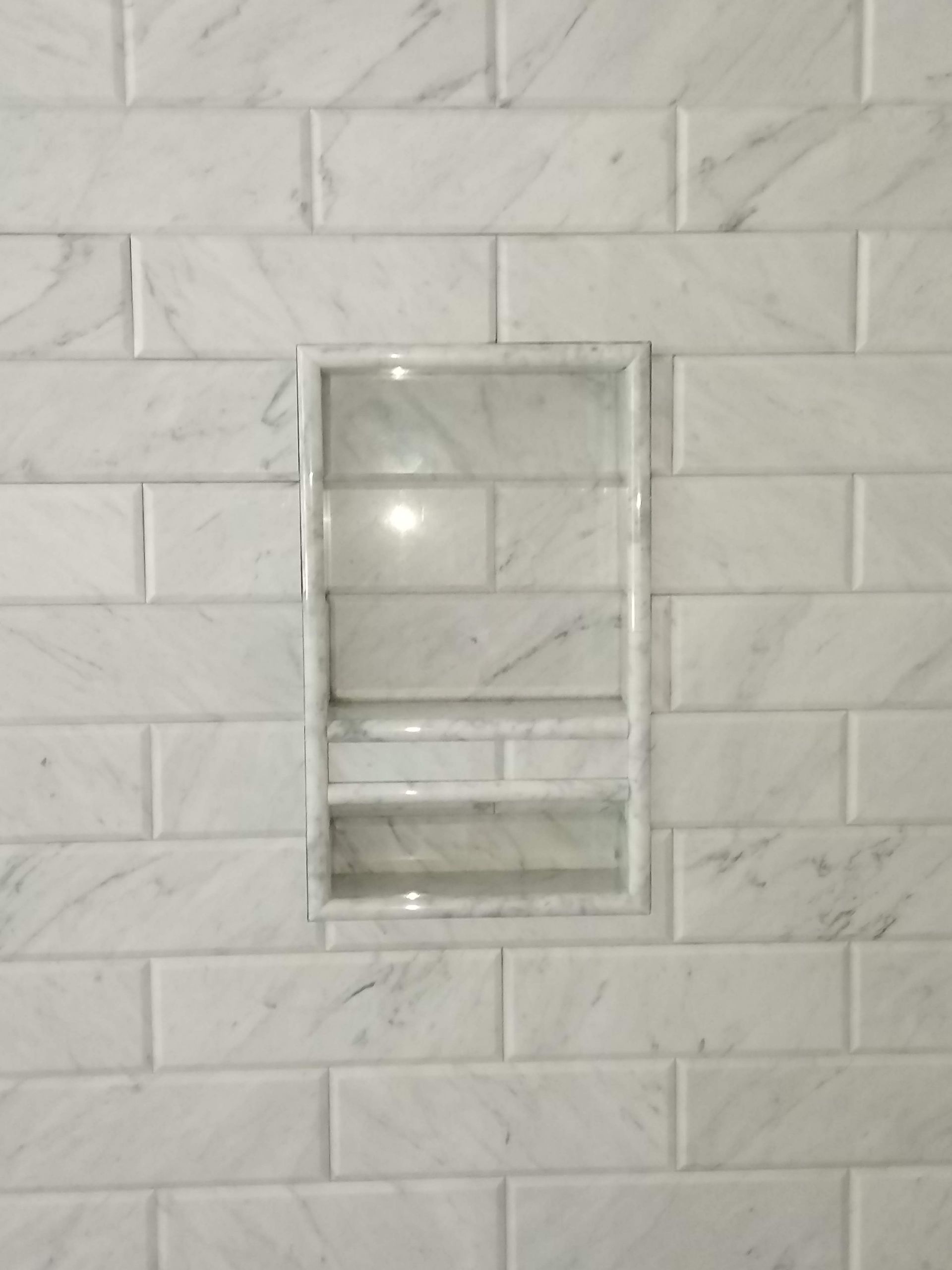 Small wall-mounted clear plastic holder on a white tiled wall.