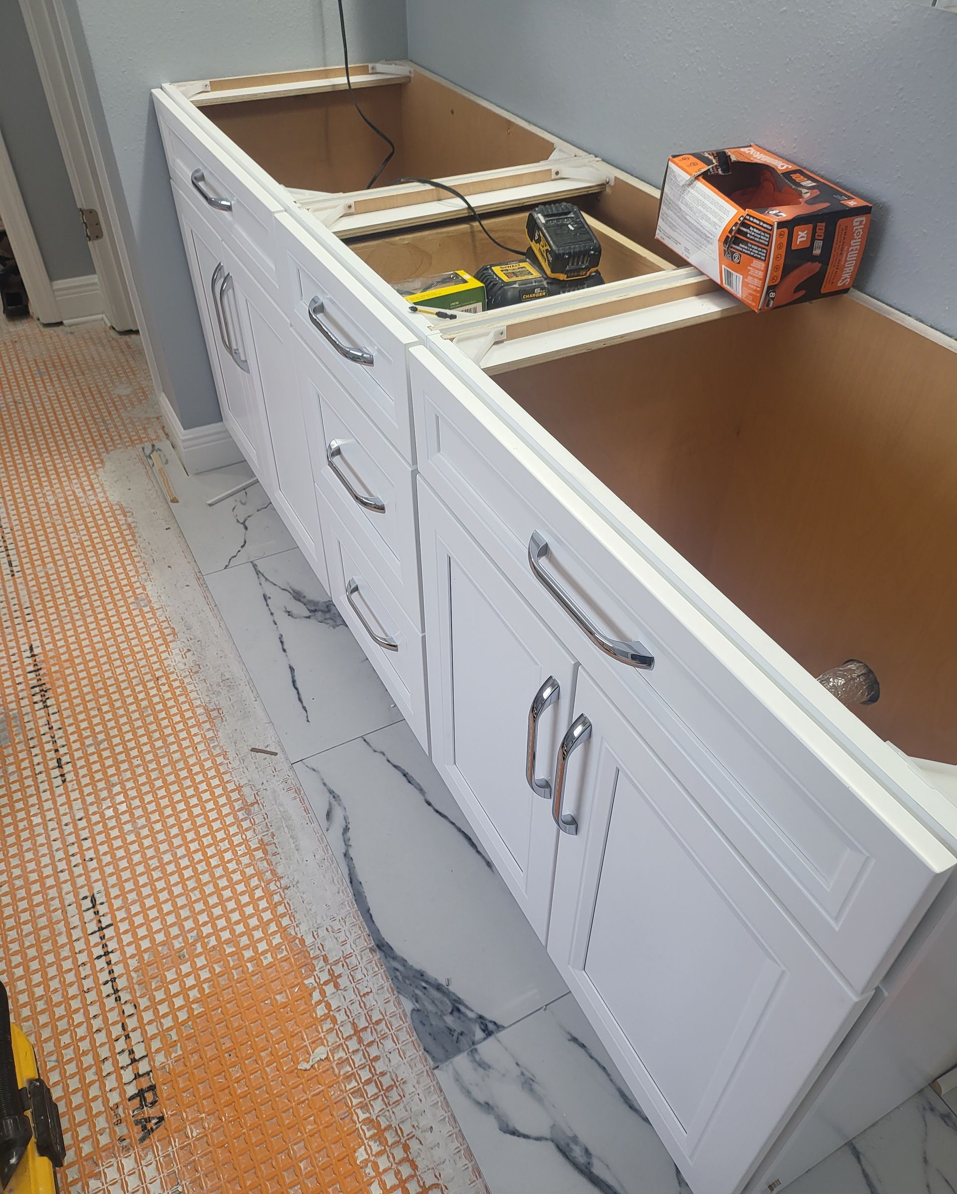 Damaged white bathroom vanity with countertop removed, exposing the interior and plumbing area