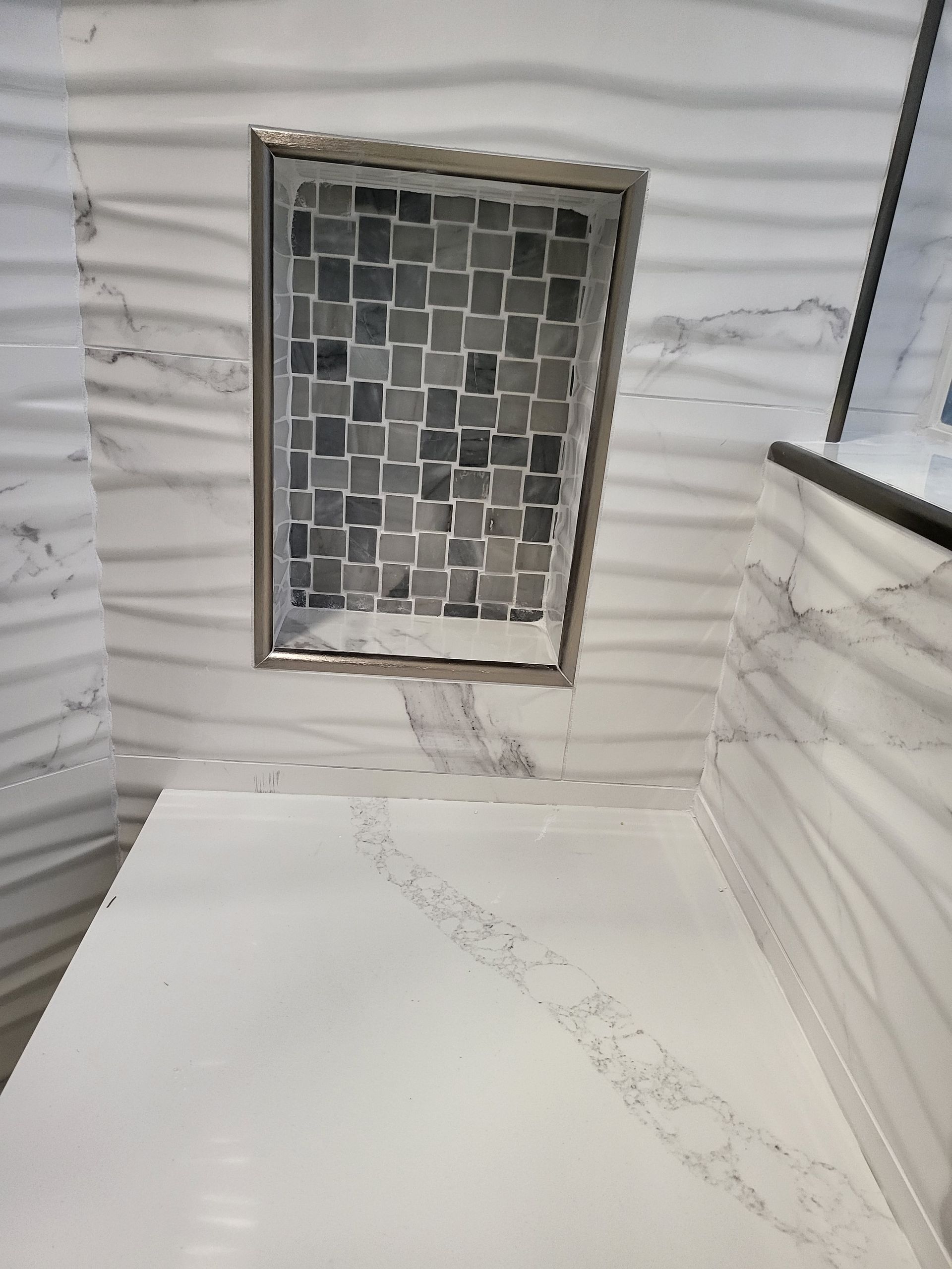 White tiled shower stall with a small frosted window and a dark handrail on the right.