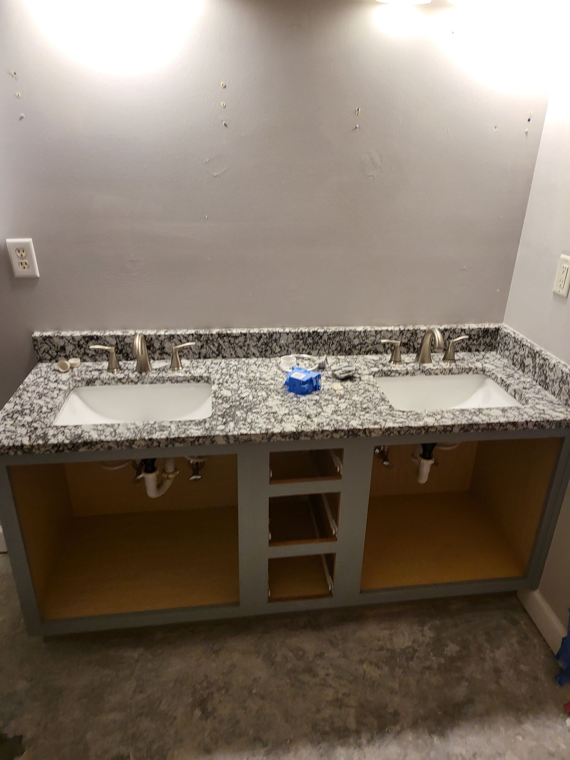 Empty bathroom vanity with speckled granite countertop, sink cutout, and unfinished cabinet openings beneath.