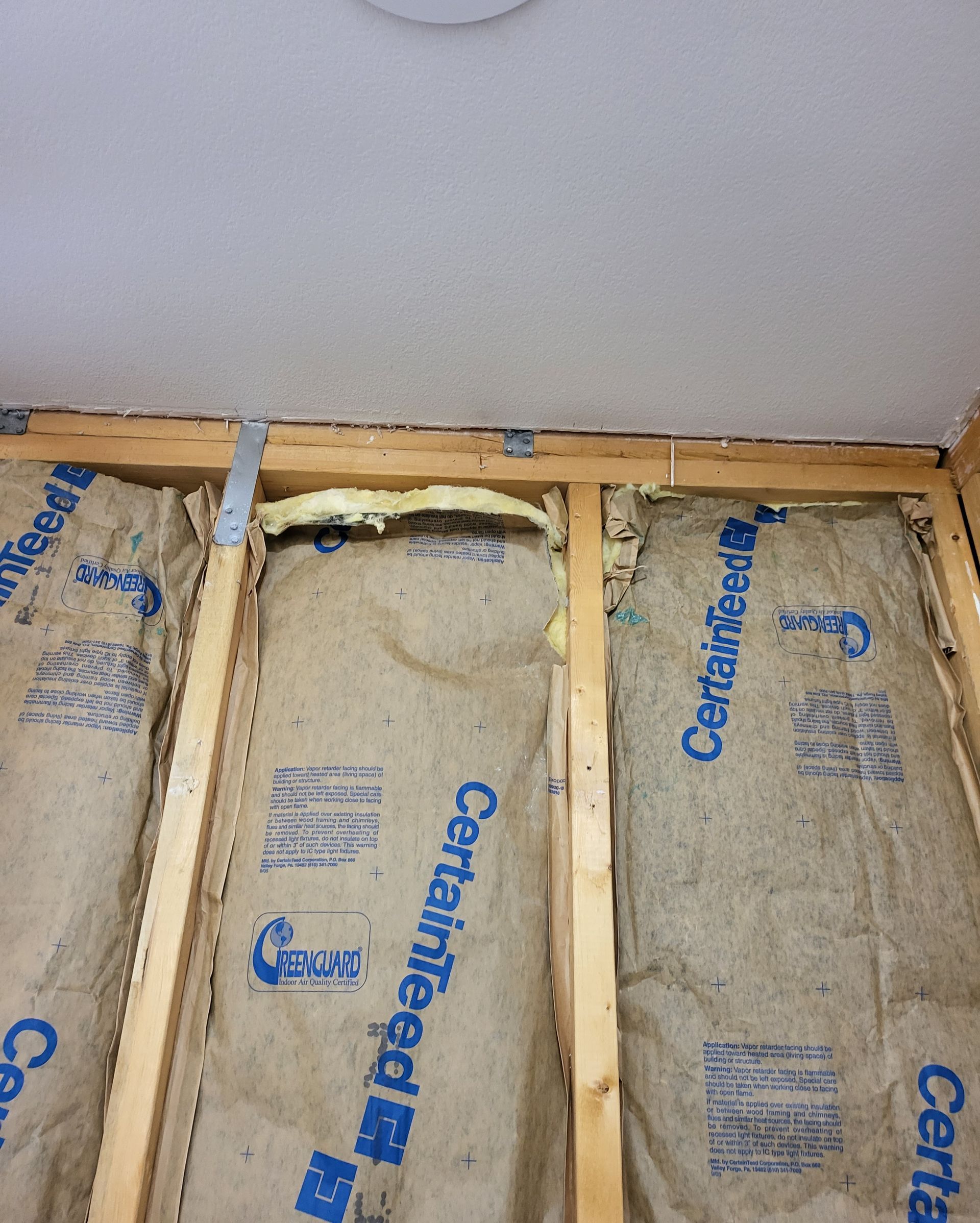 Open floor with exposed joists and yellow fiberglass insulation between beams.