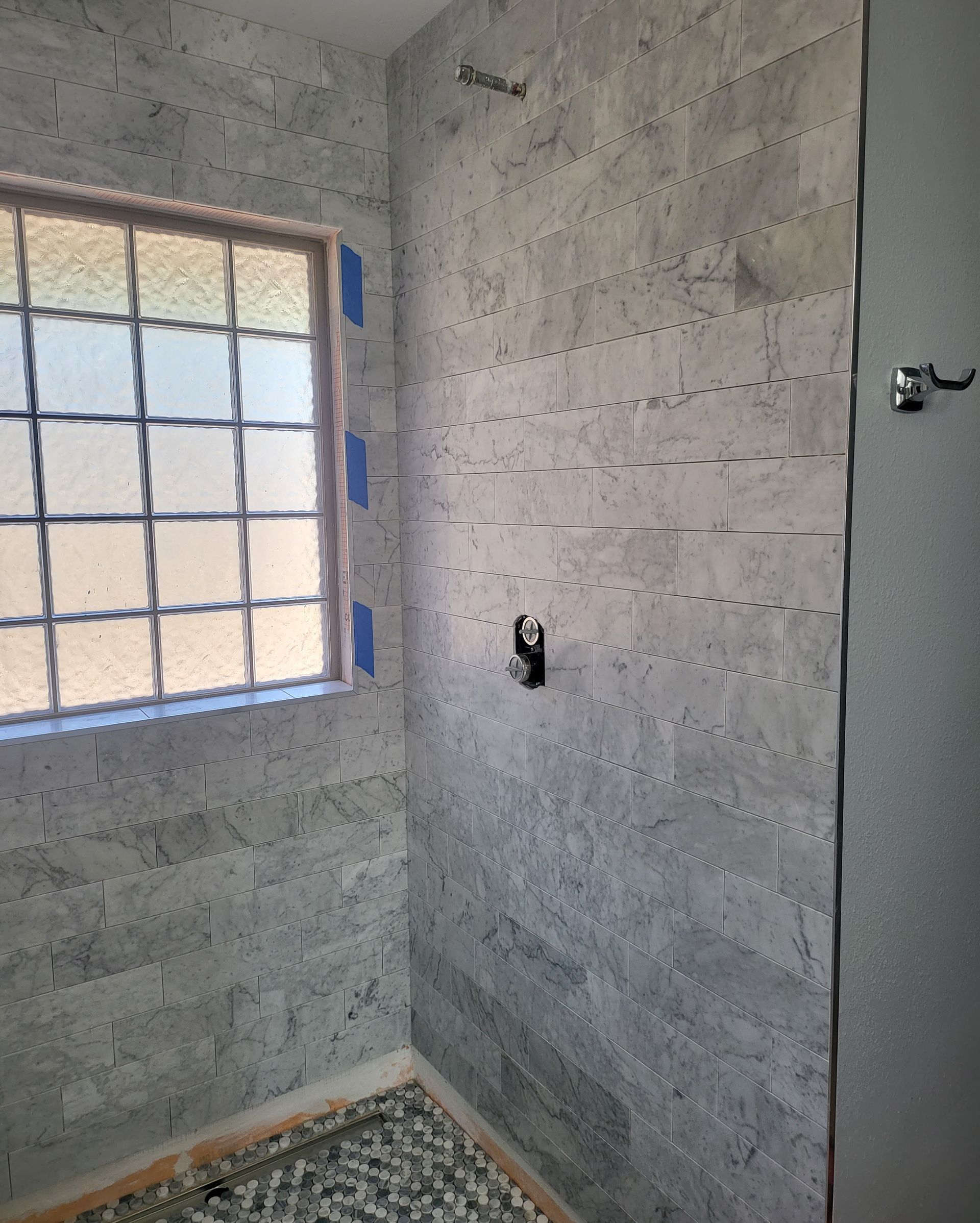 Small unfinished bathroom with gray concrete walls, a window, and exposed electrical outlet.