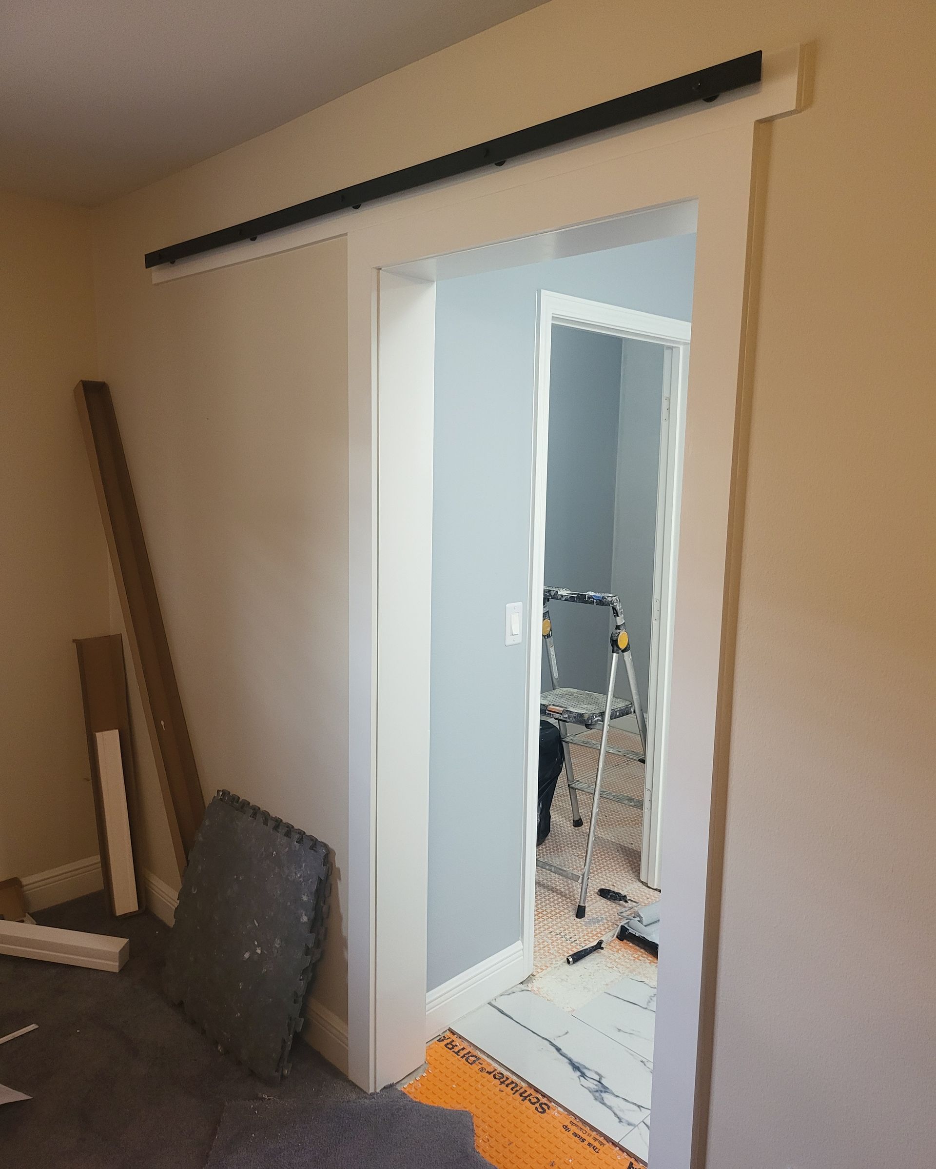 Partially installed sliding door opening into a hallway, with tools and materials nearby.