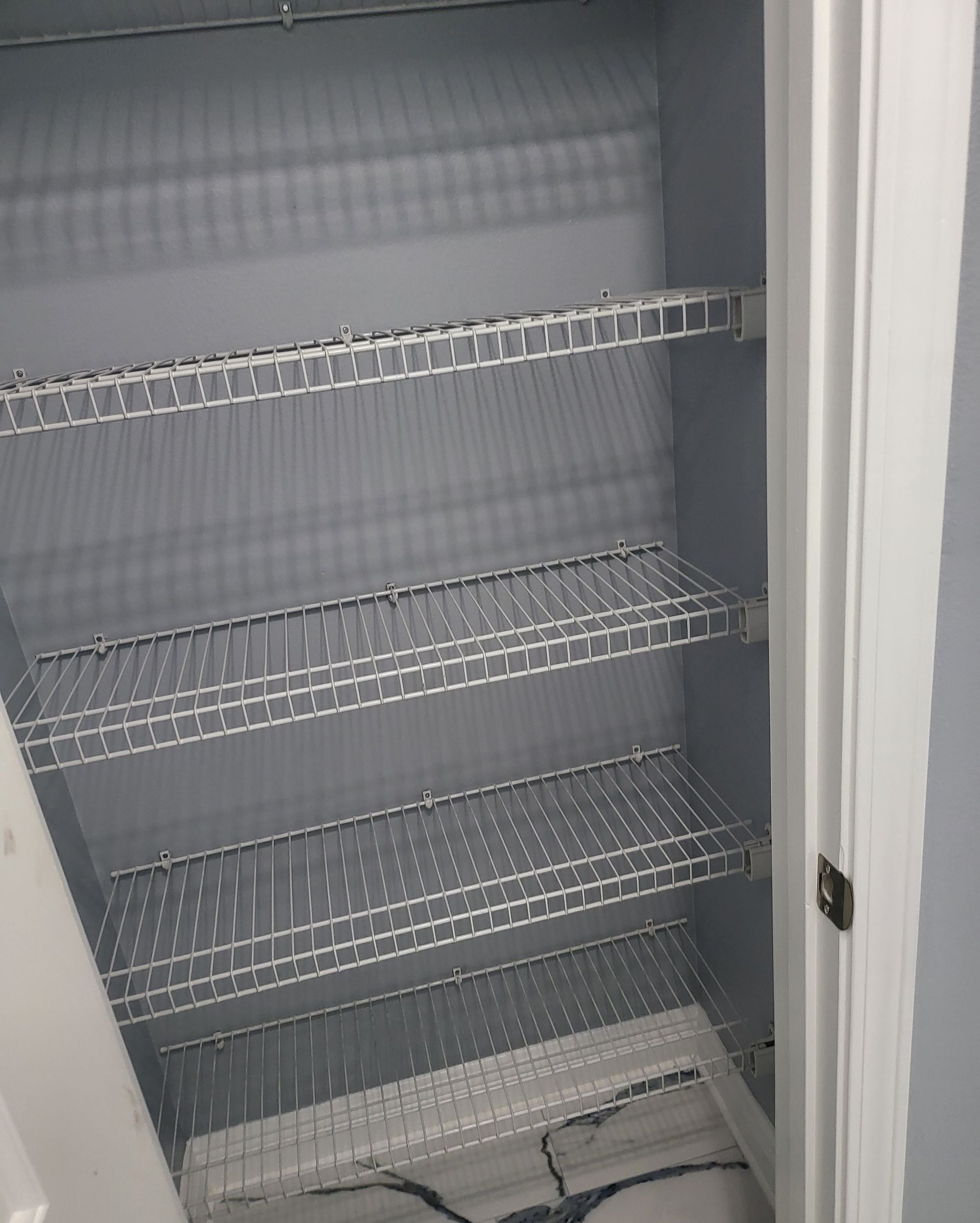 Open refrigerator with empty wire shelves inside and a door seal visible on the right