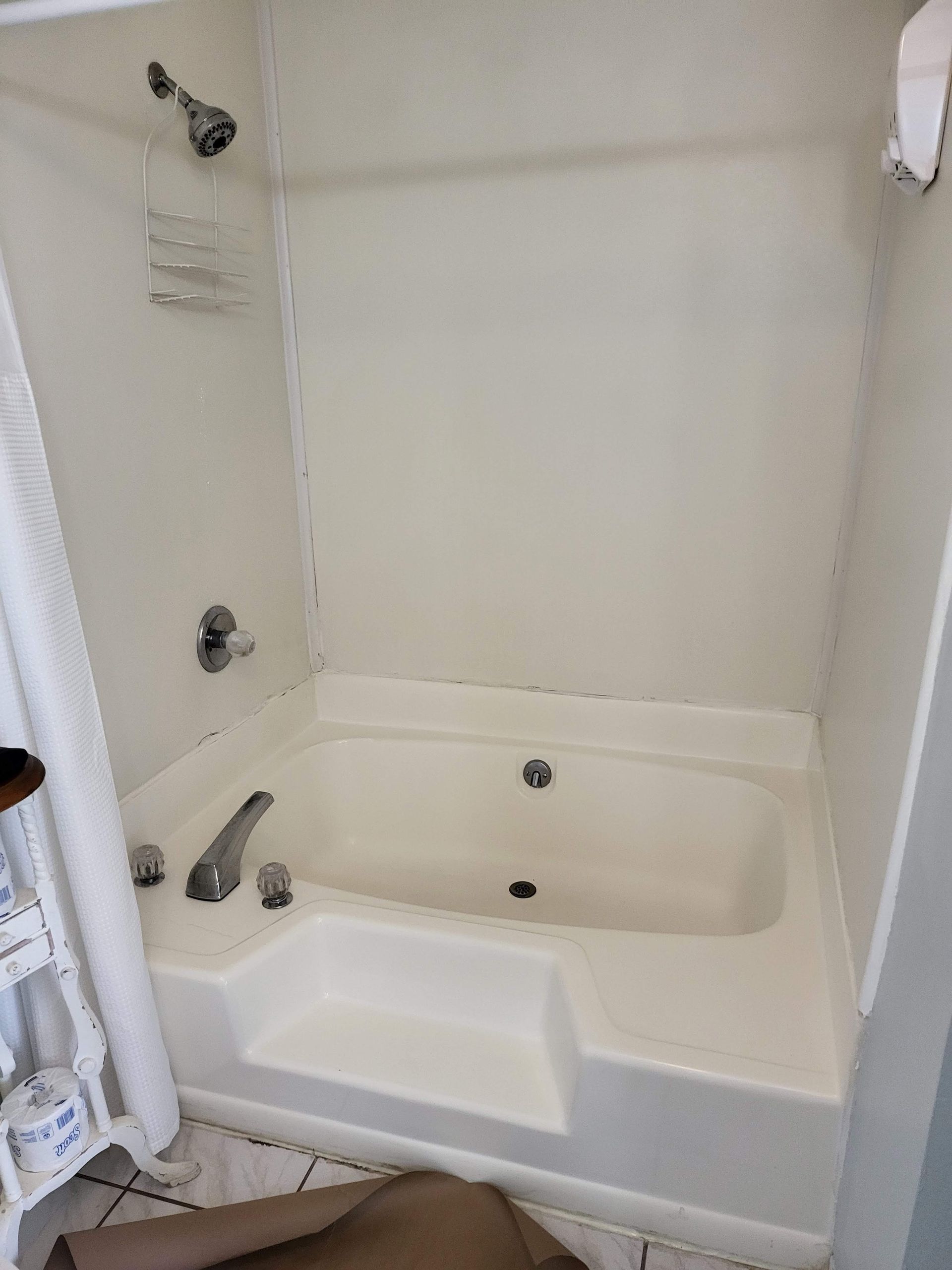 White bathtub and shower combo in a small bathroom with a chrome faucet and showerhead.